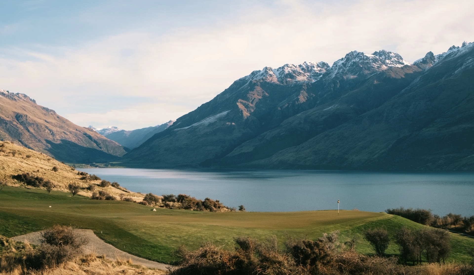 An alpine golf course beside a lake framed by mountains