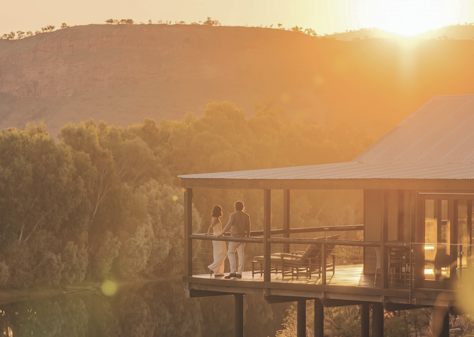 A couple watches the sunset from the deck of a remote lodge