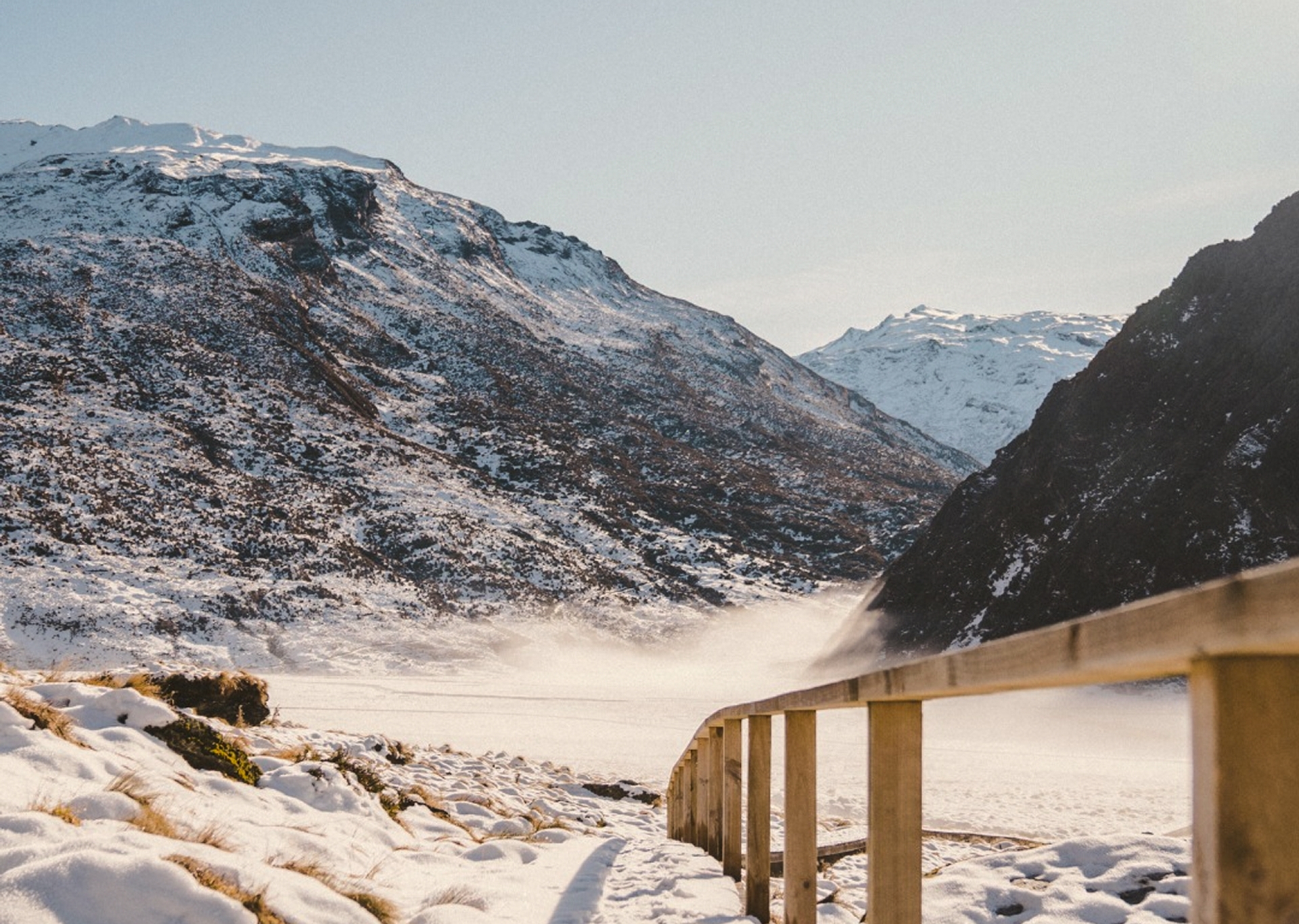 A timber bridge through a snow-covered mountain valley