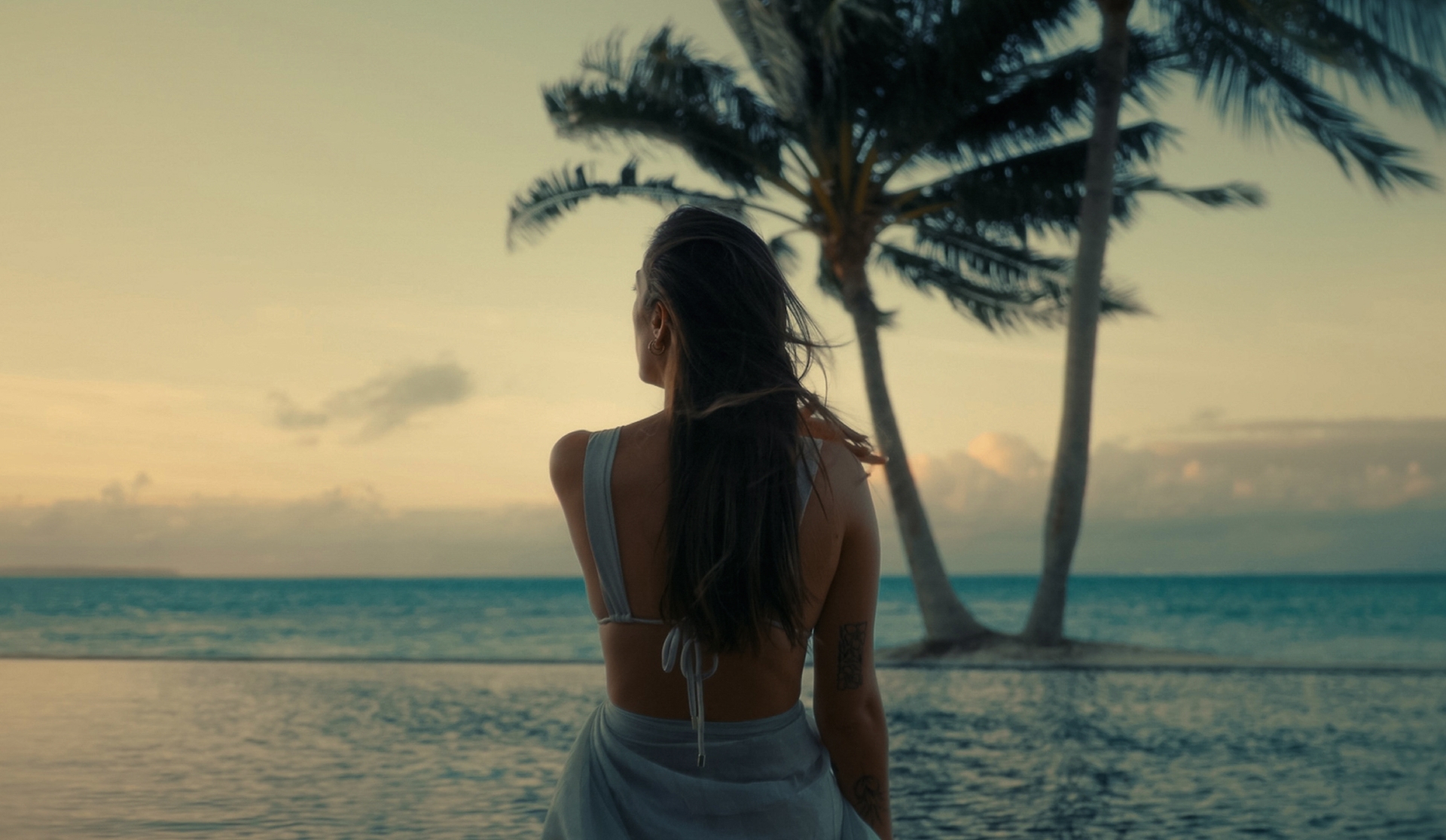 A traveller looks out to a South Pacific lagoon at dusk