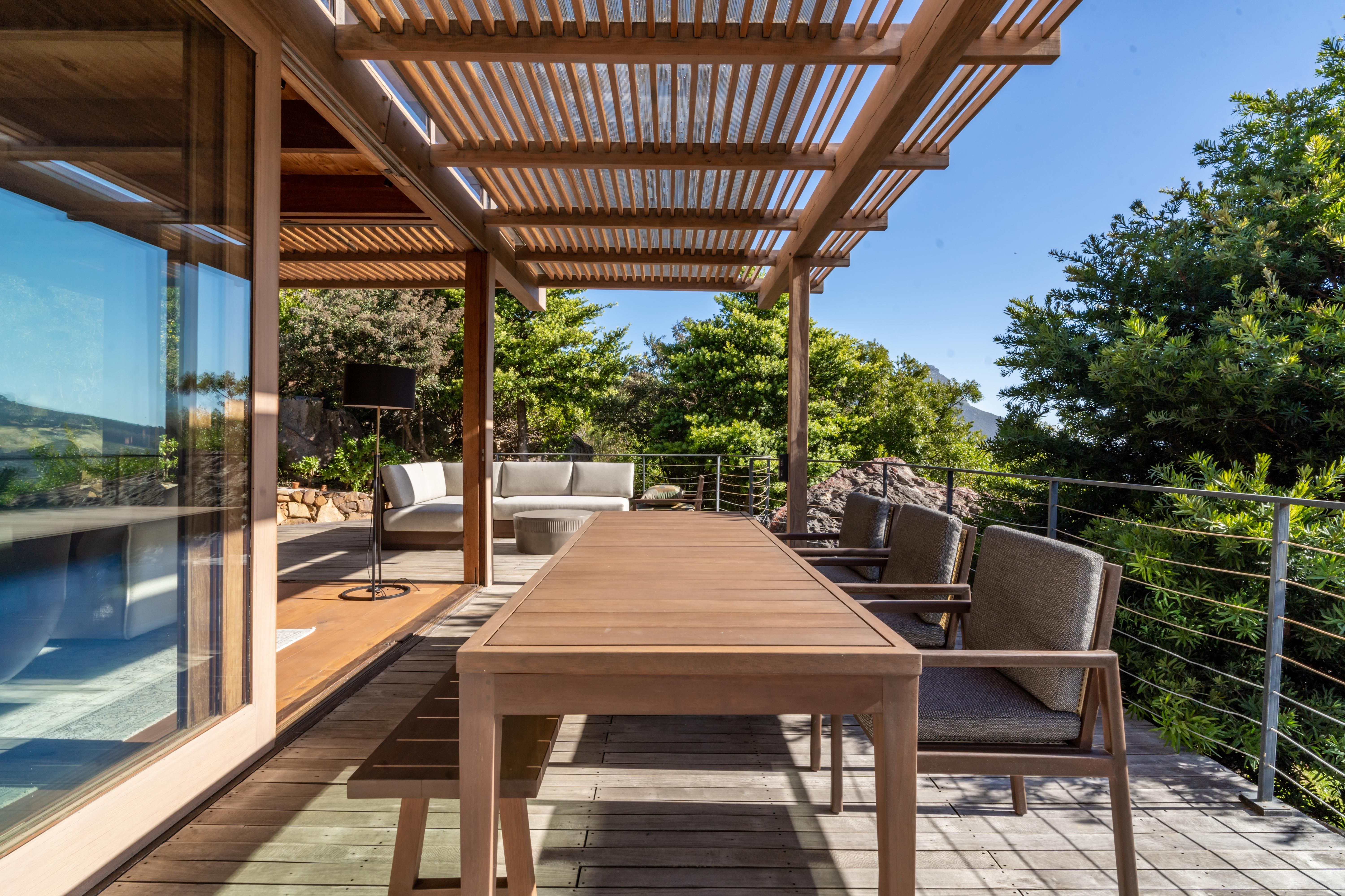 Outdoor dining table under the pergola, looking across the valley