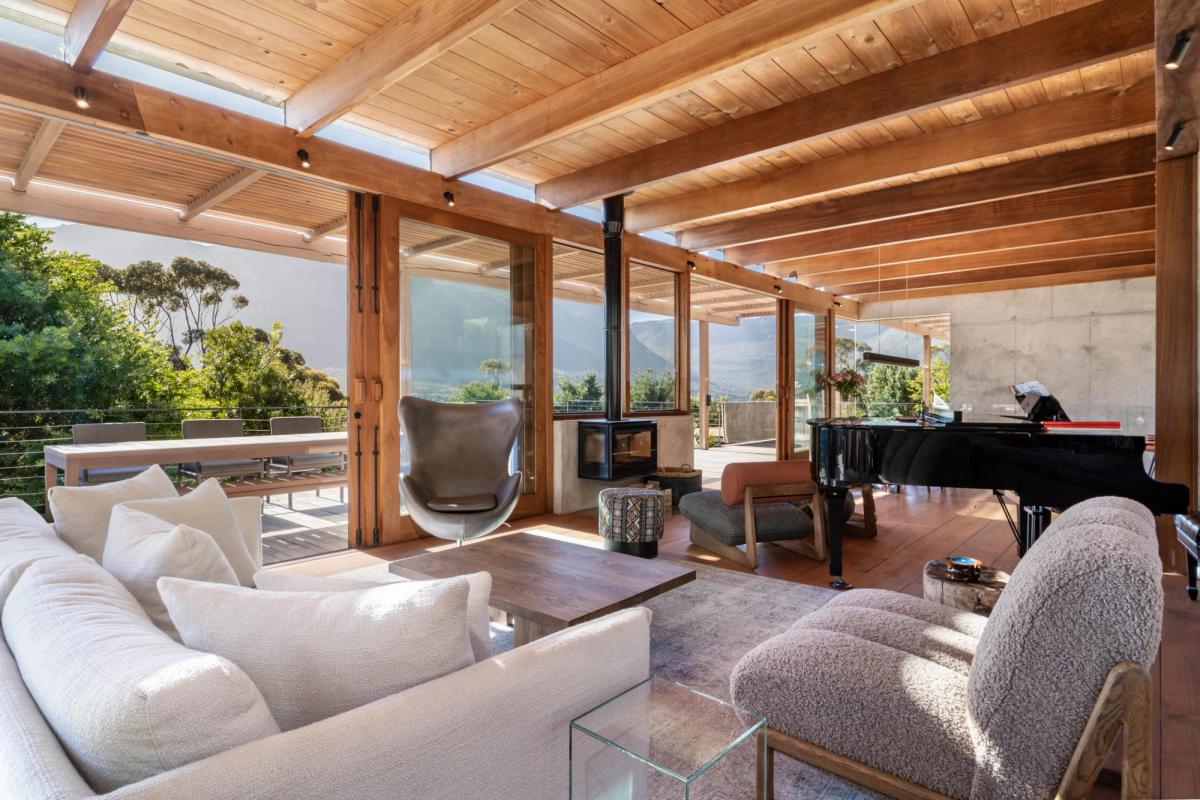 Living room: grand piano + sofas + wood-fired stove + mountain through the glass