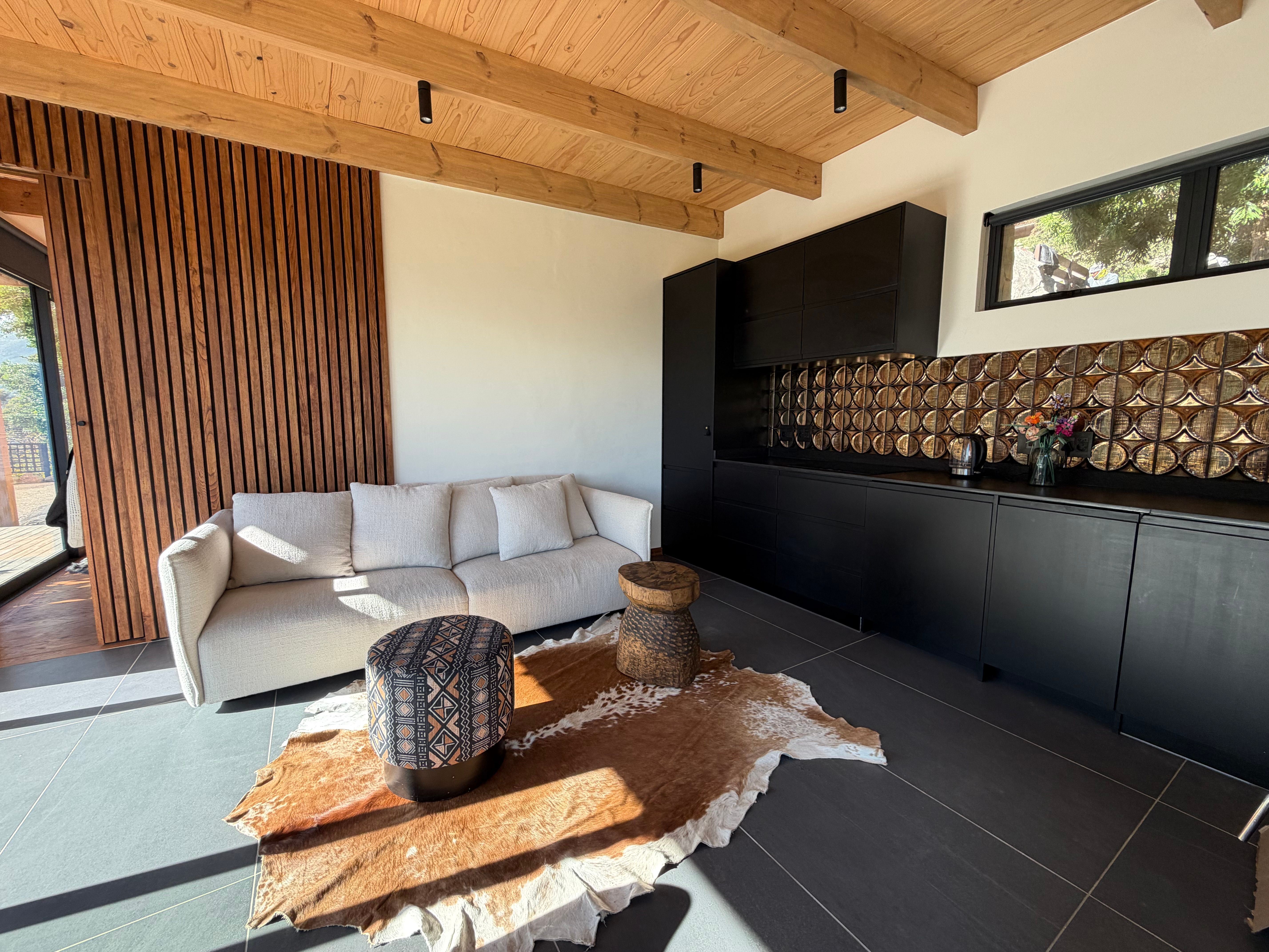 Guest Cottage living area with linen sofa, kilim rug, slatted wall, slate floor