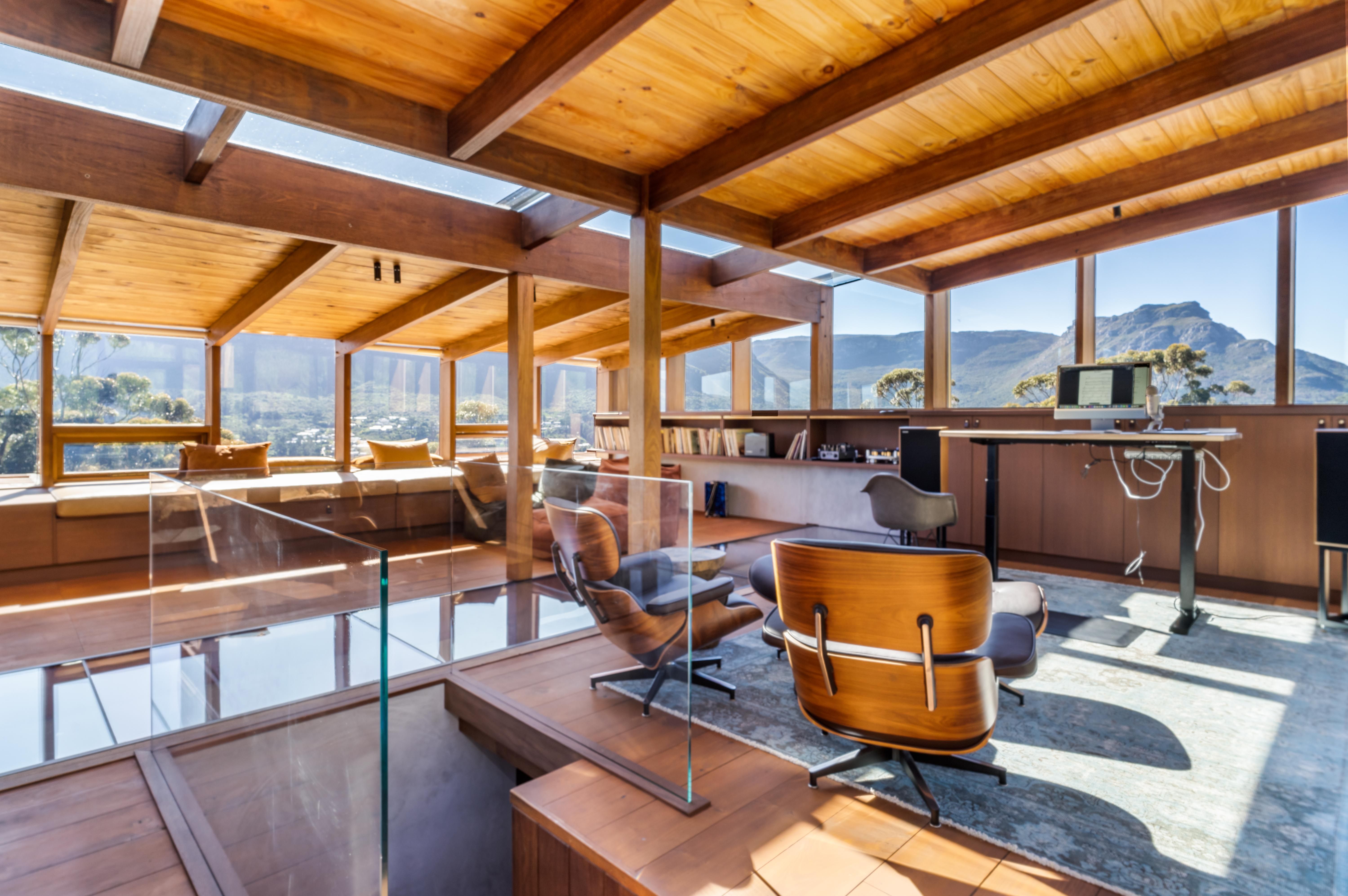 Upstairs studio with two Eames lounges, glass floor, and clerestory windows framing the mountain