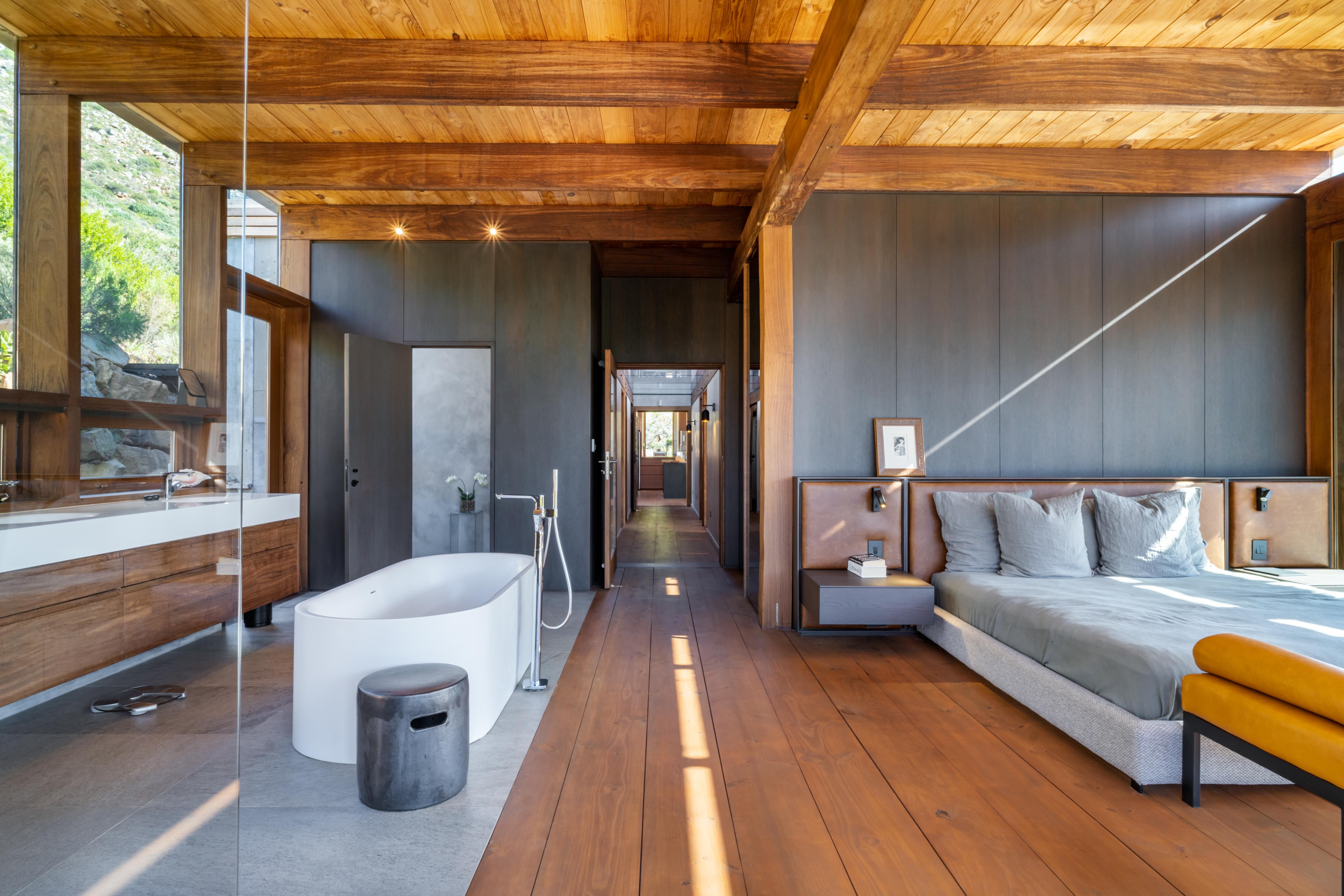 Master suite: bed + freestanding bath + mountain through the glass