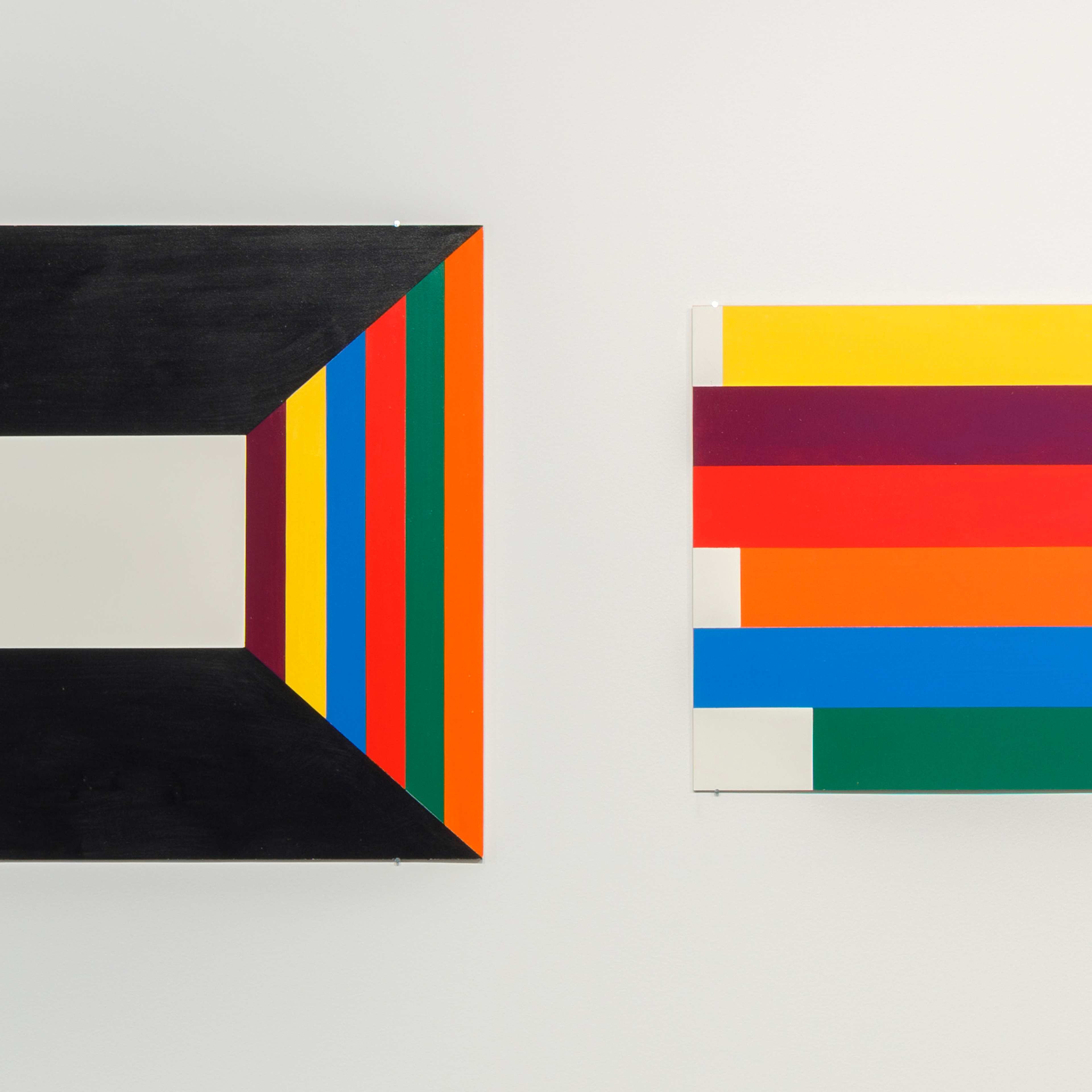 Four abstract geometric paintings hang on a white wall, each featuring bold, colourful shapes and patterns, including stripes, rectangles, and one solid orange square on the far right.
