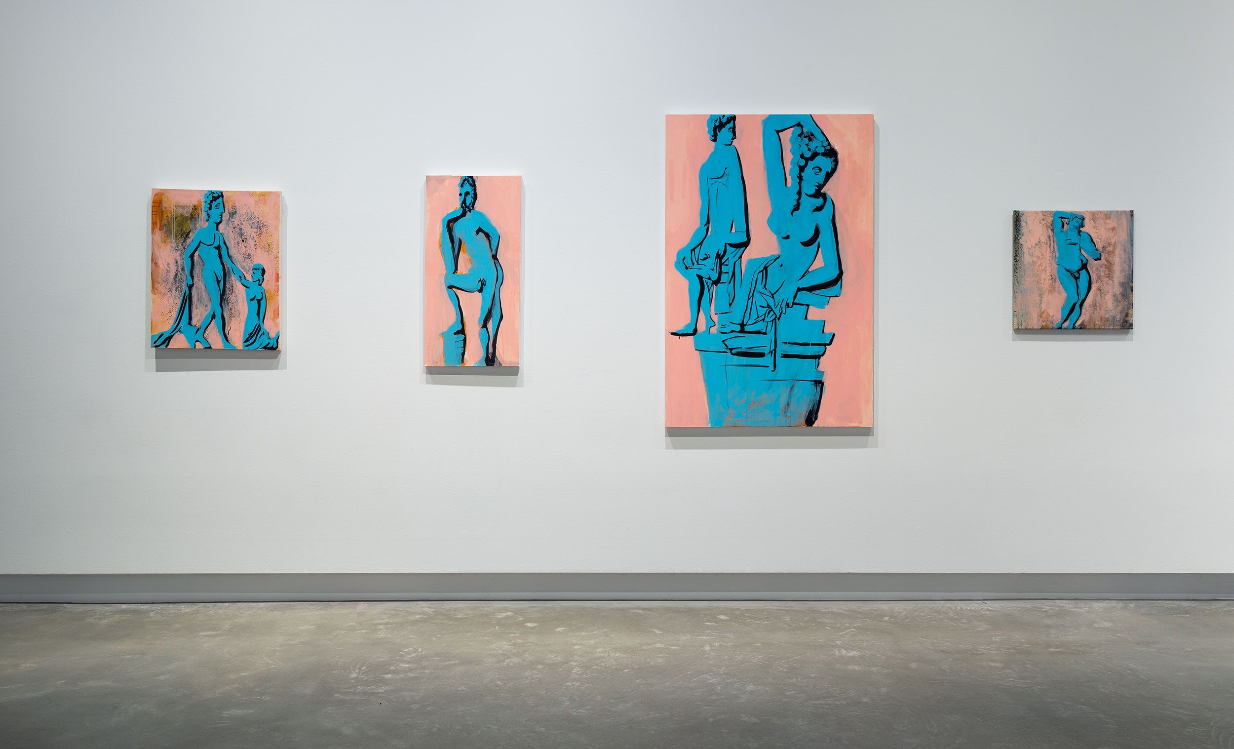 Four paintings of blue classical-style statues on pinkish backgrounds are displayed on a white gallery wall above a concrete floor. The artworks vary in size and depict different poses of standing and seated figures.