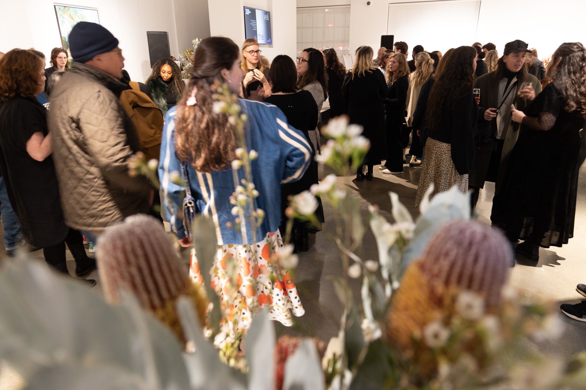 A room of people talking and eating with a bouquet of native australian flowers in the foreground.