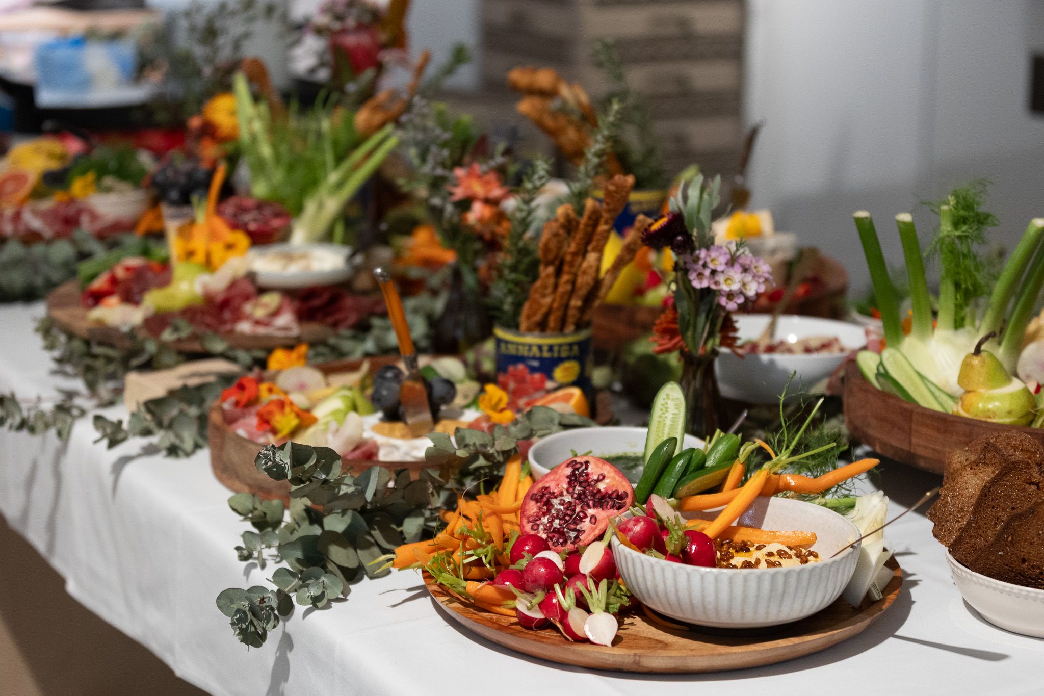A table of colourful and delicious finger food. Pomegranate, cheese, meat, fruits and vegetables line the table in a highly decorative way