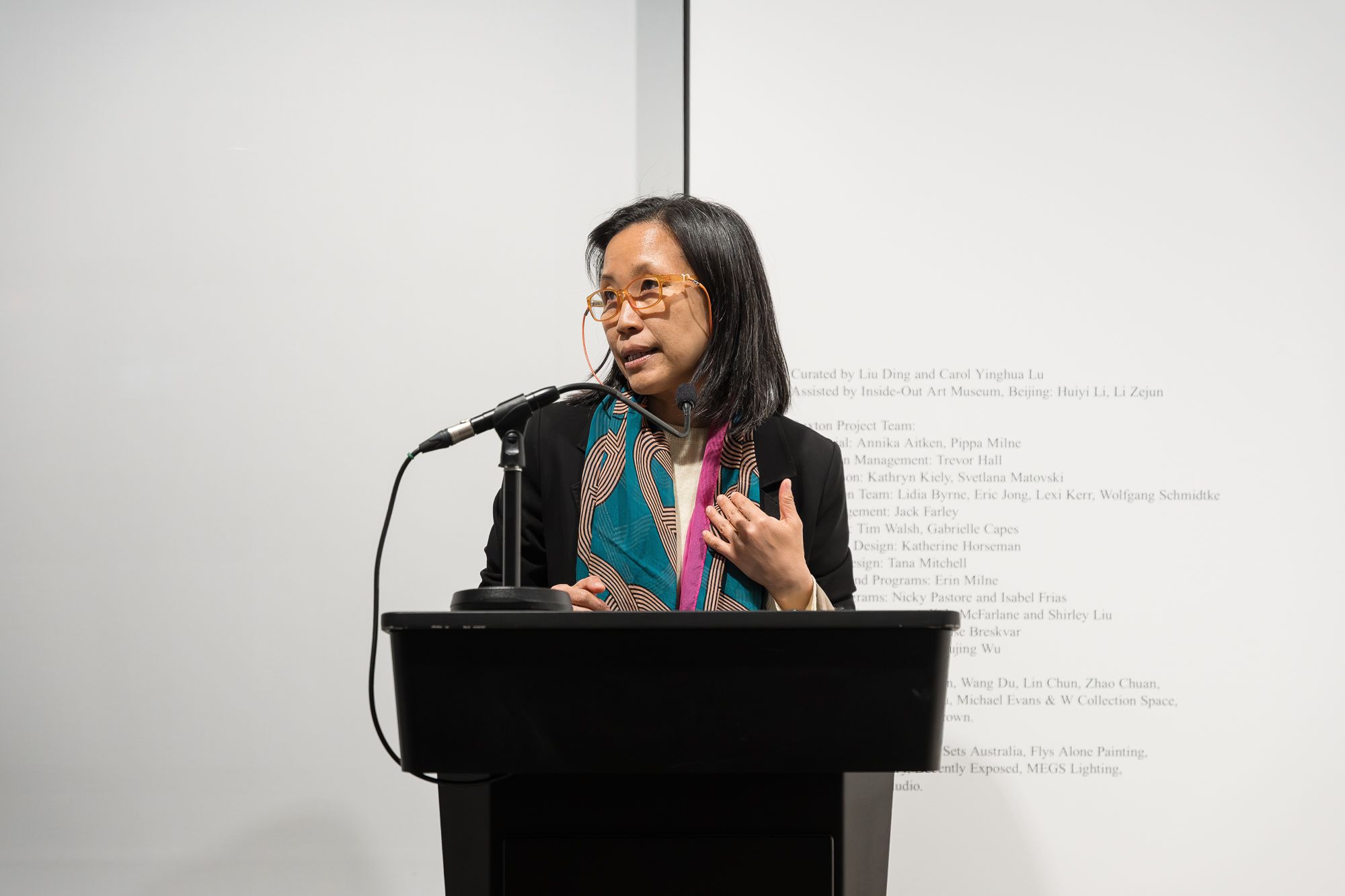 Carol Yinghua Lu speaking into a mic on a lectern.