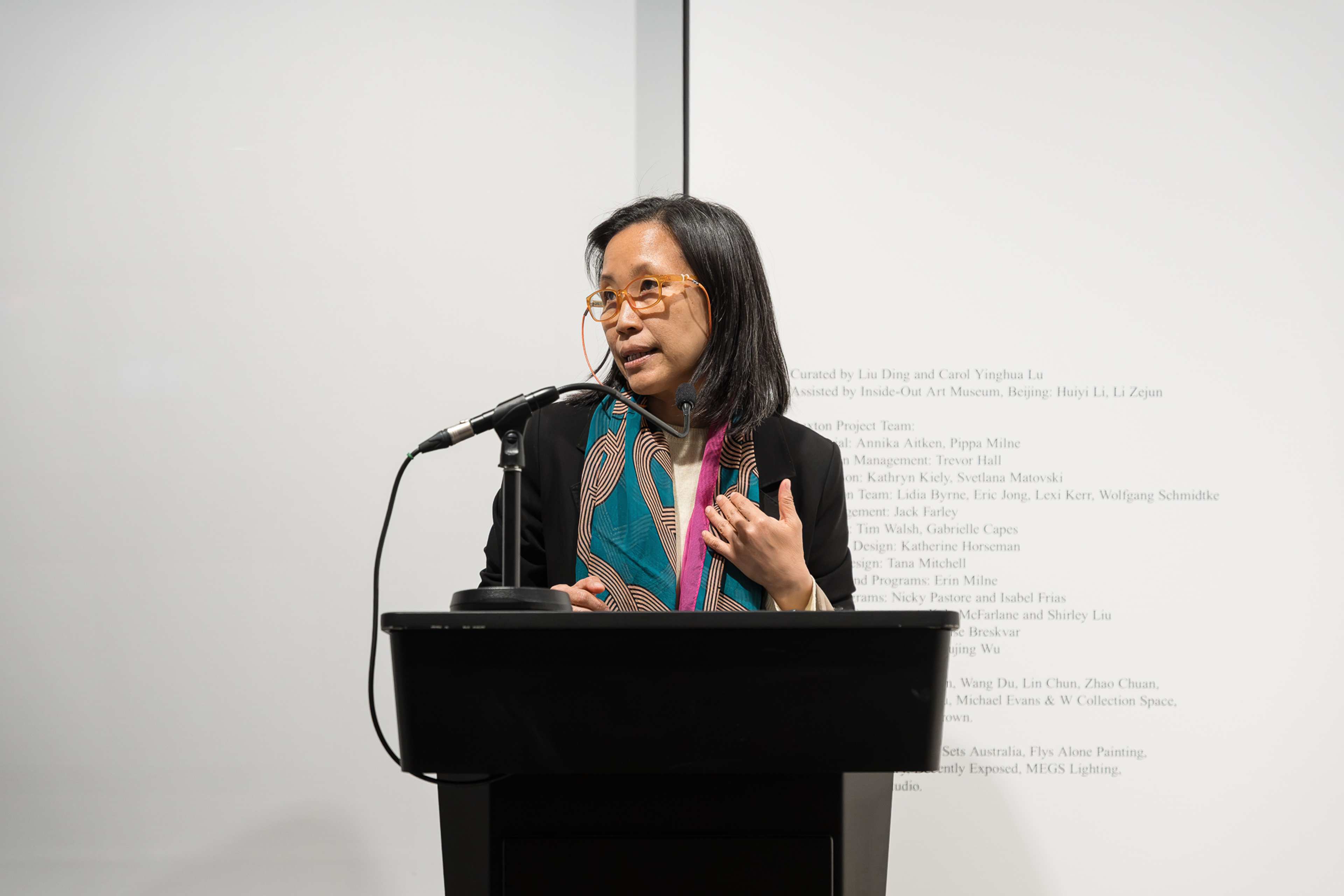 Carol Yinghua Lu speaking into a mic on a lectern.