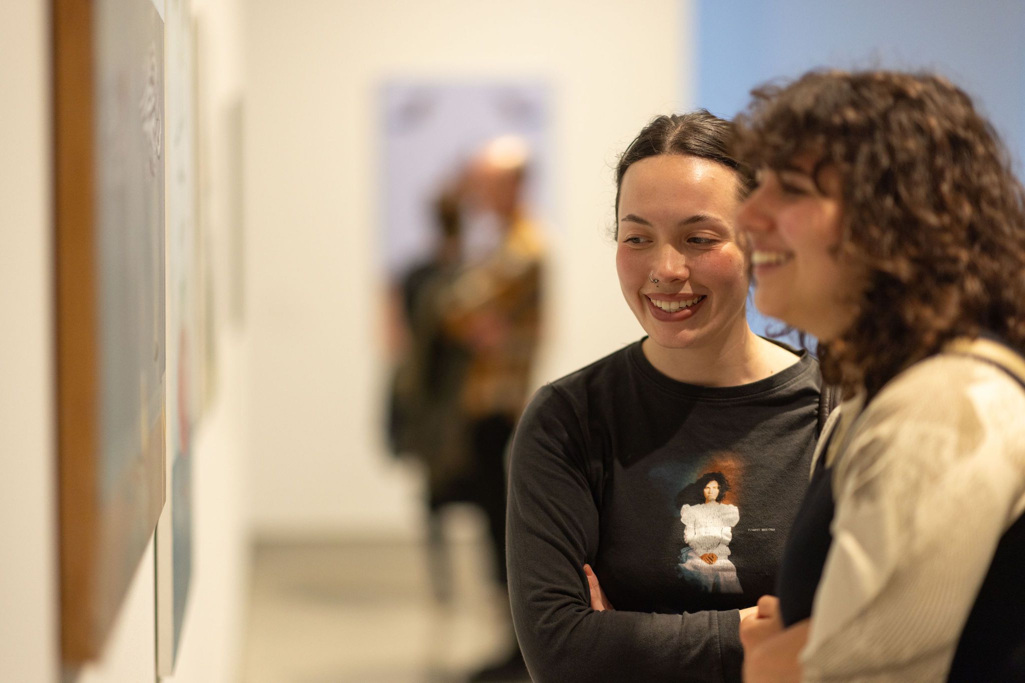 Two students look at art smiling in a gallery