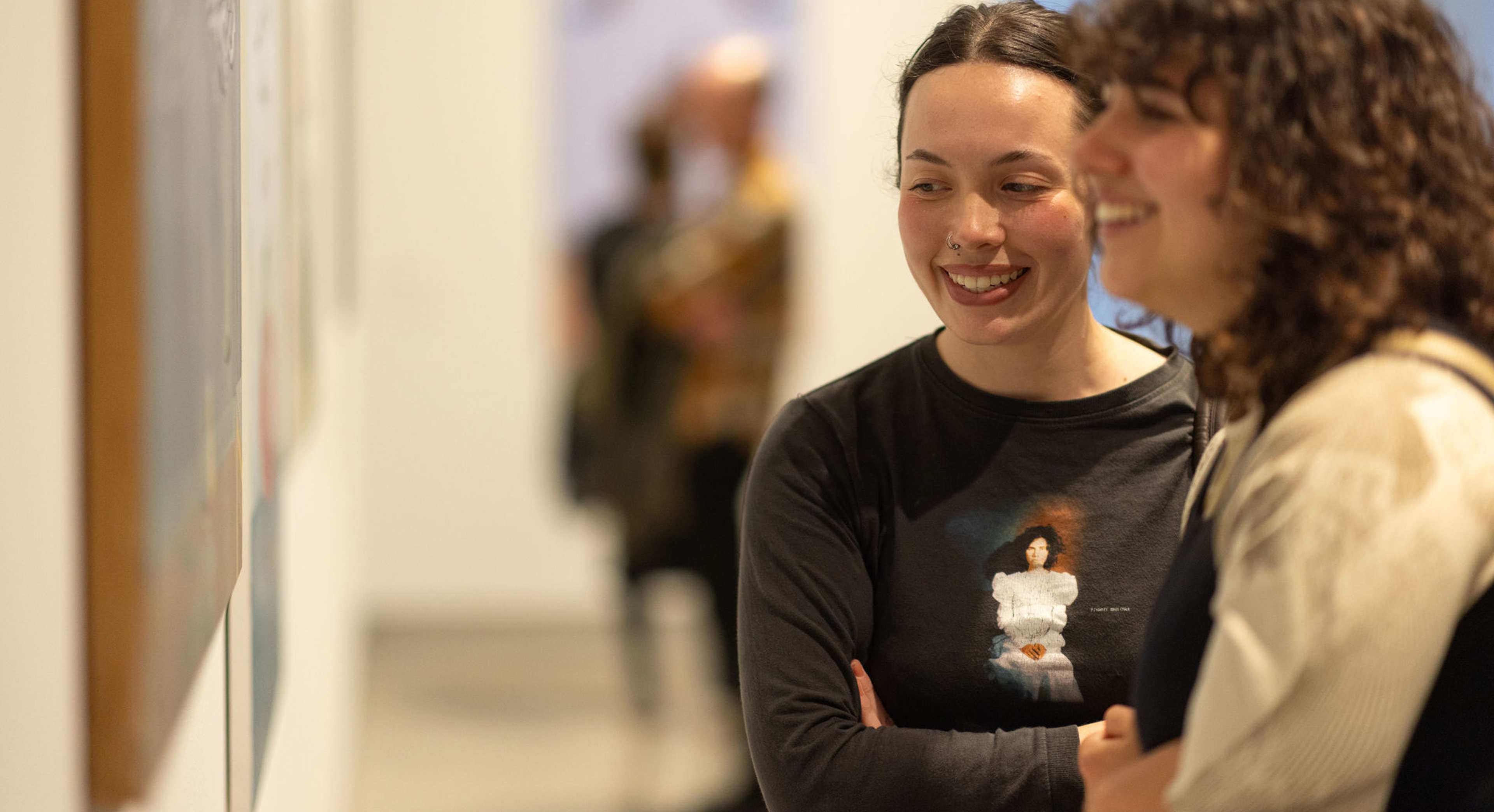 Two students look at art smiling in a gallery