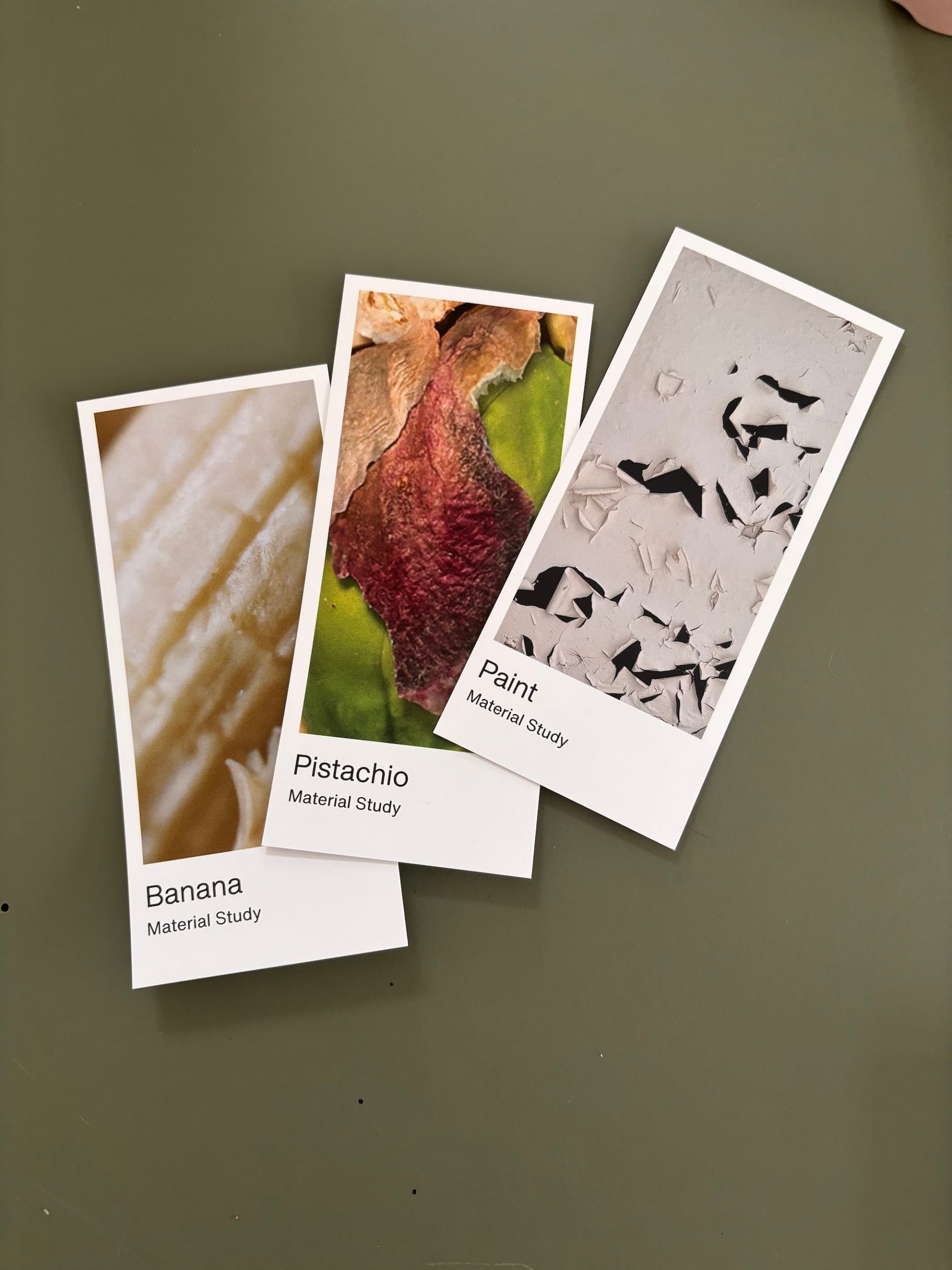 Three rectangular cards labeled Banana, Pistachio, and Paint display close-up texture images as part of a Material Study on a green surface.