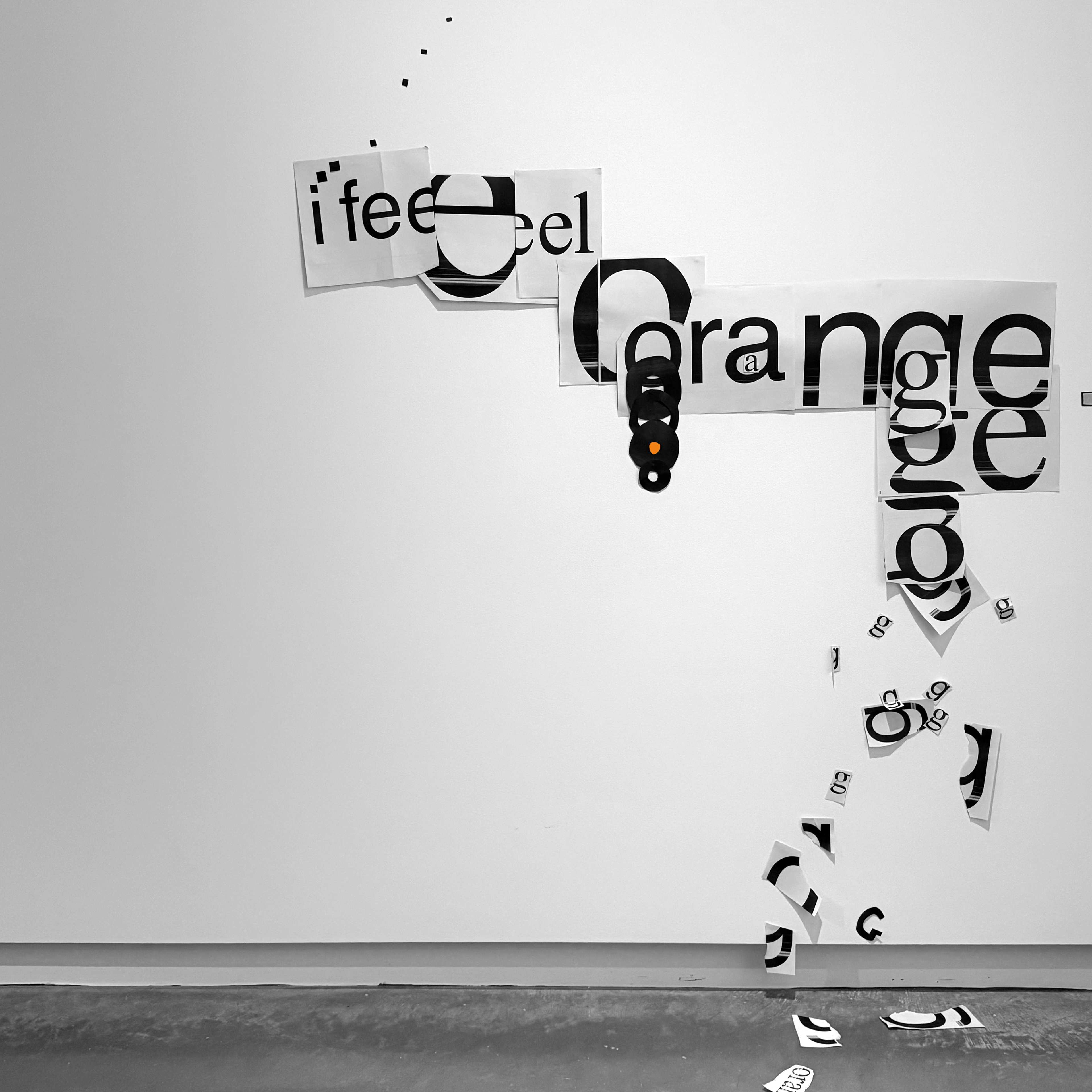 Cut out paper pasted to the wall loosely reads, 'i feel orange'