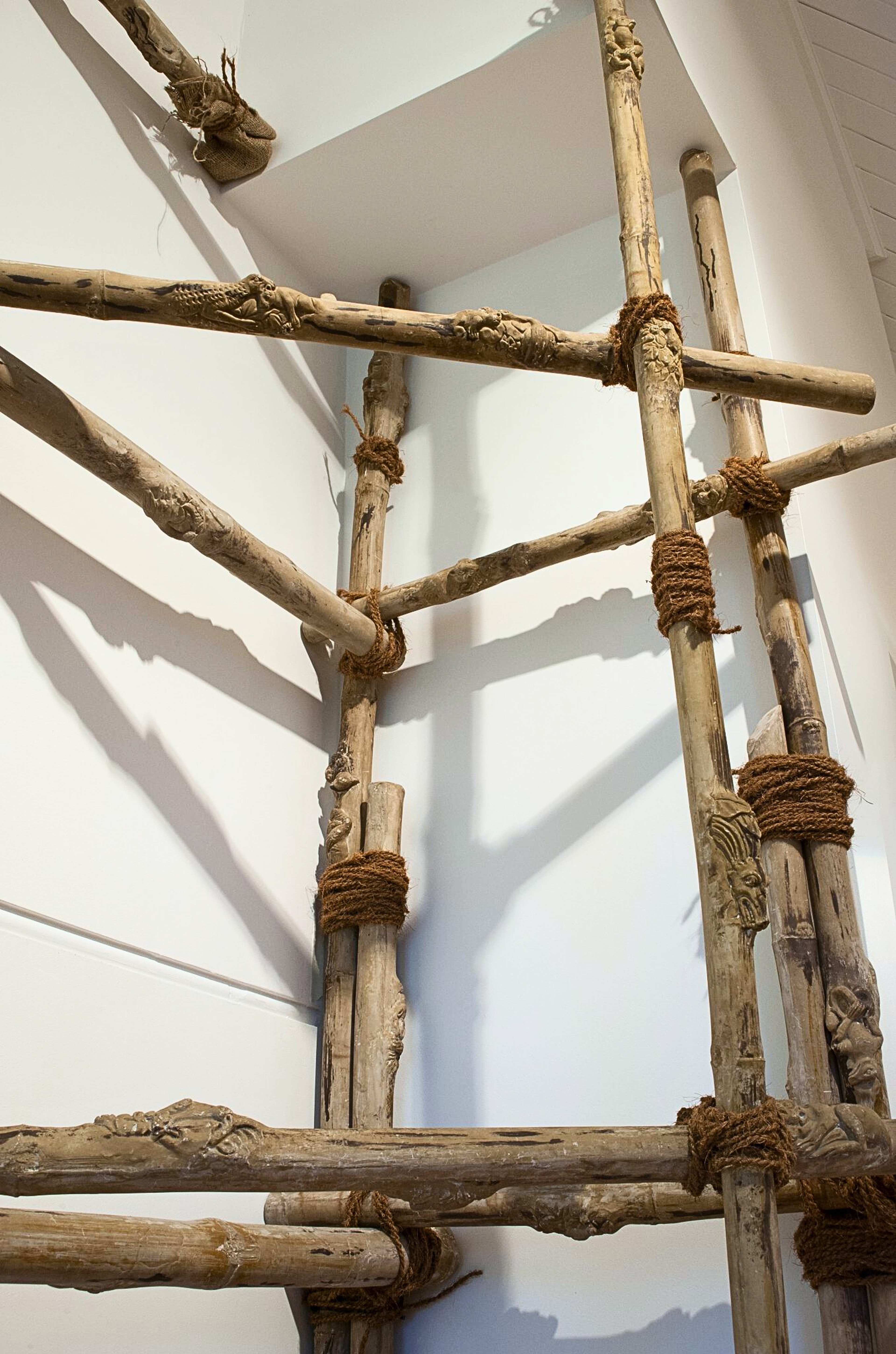A detail photograph of poles tied with rope into a vertical structure