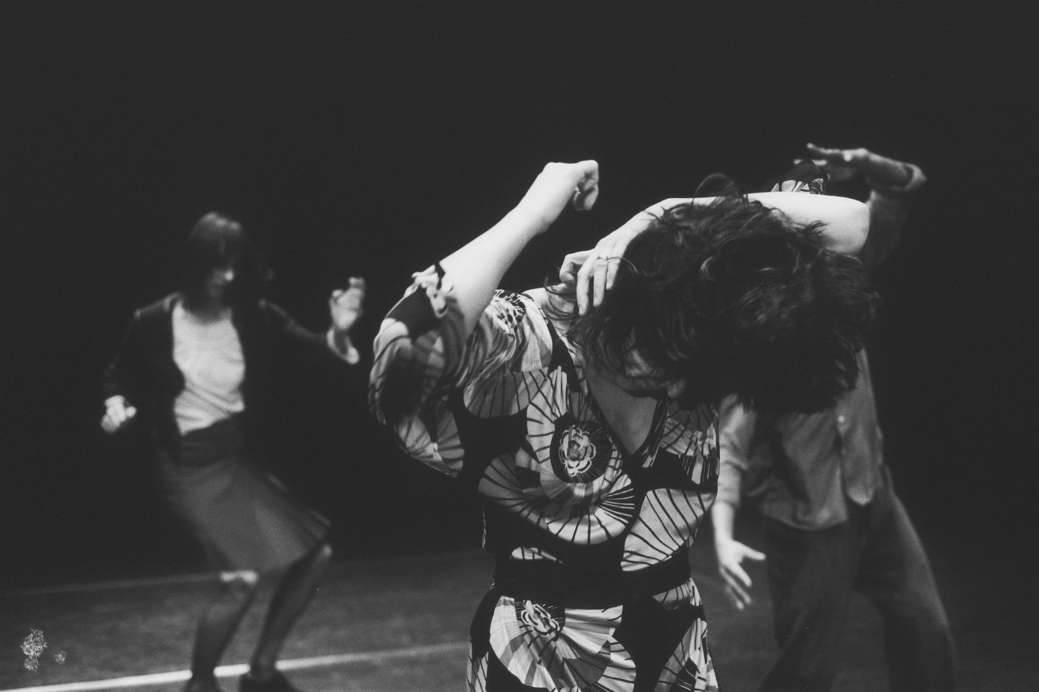 A still from a black and white film showing three people captured mid-dance