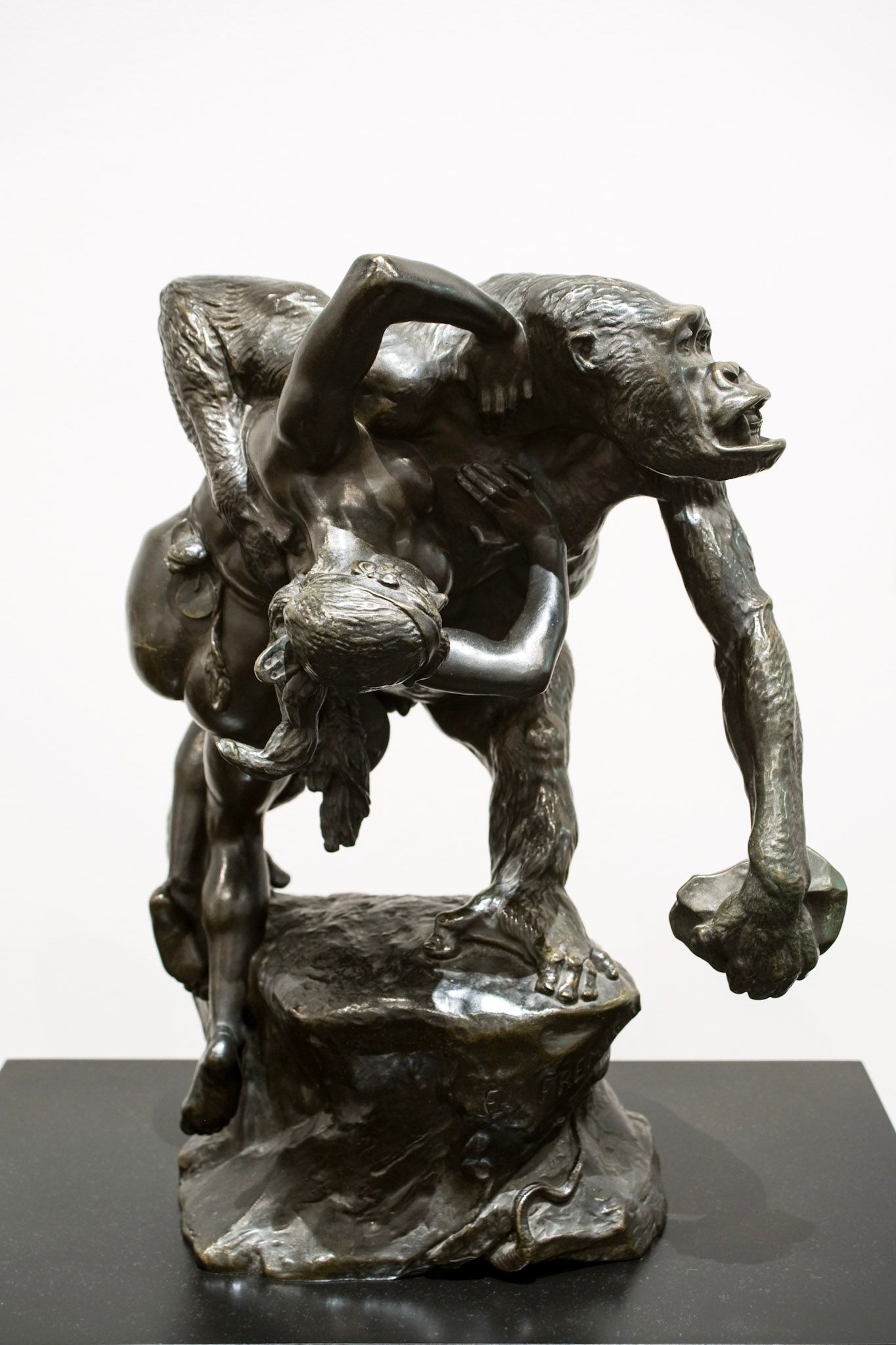 A photo of a sculpture, featuring an ape figure holding a human body