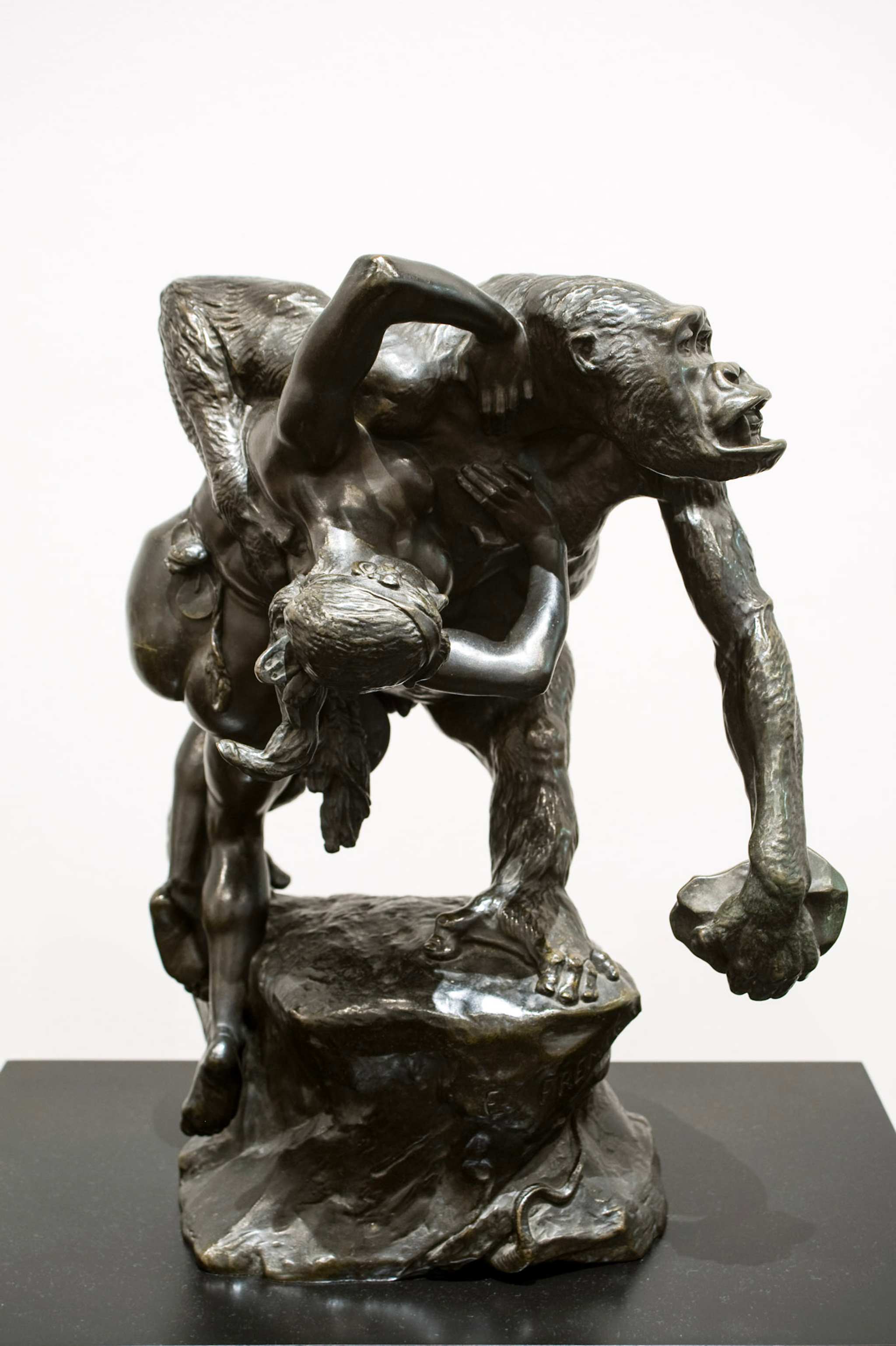 A photo of a sculpture, featuring an ape figure holding a human body