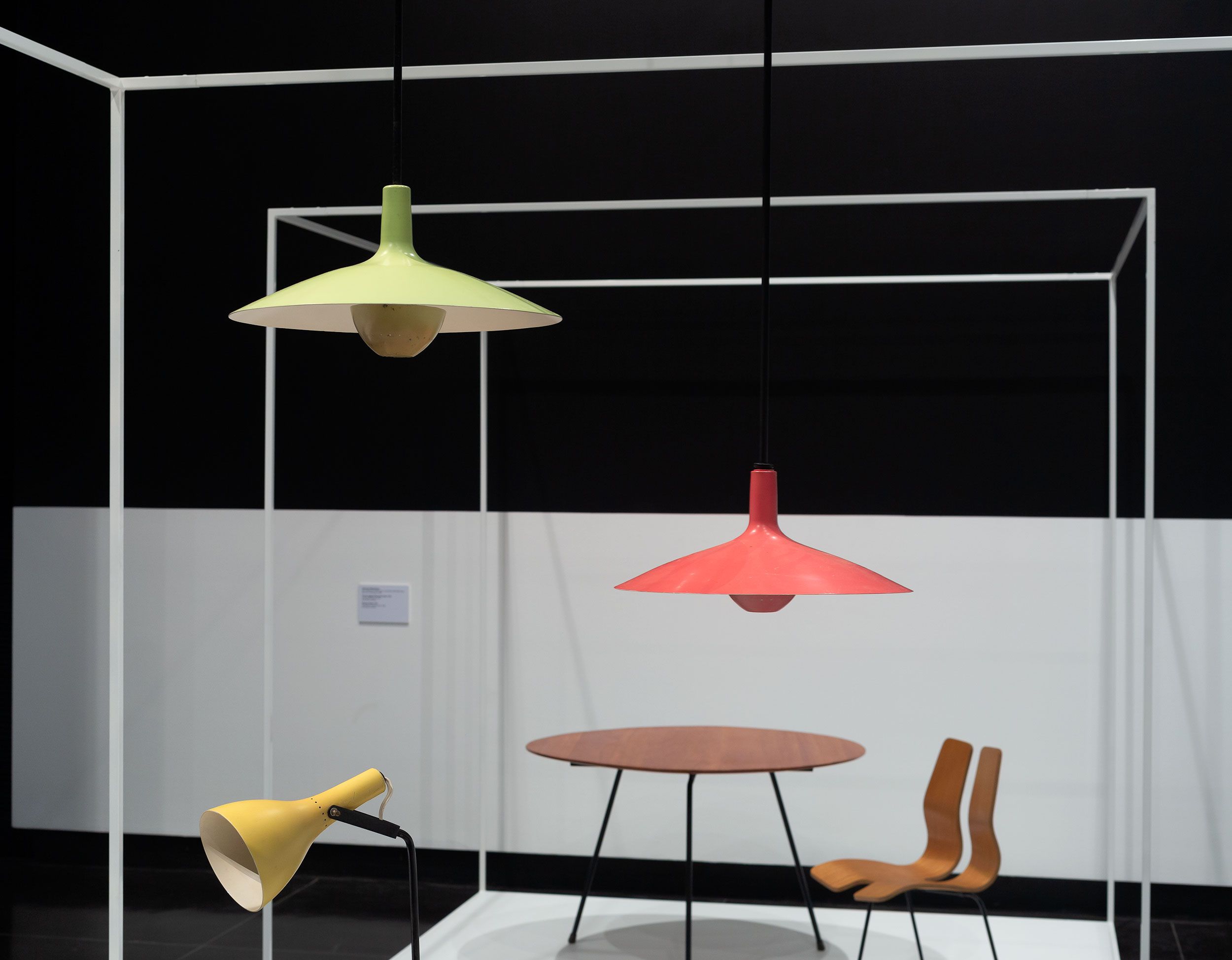 An installation of mid century brightly painted lamps with table and chair