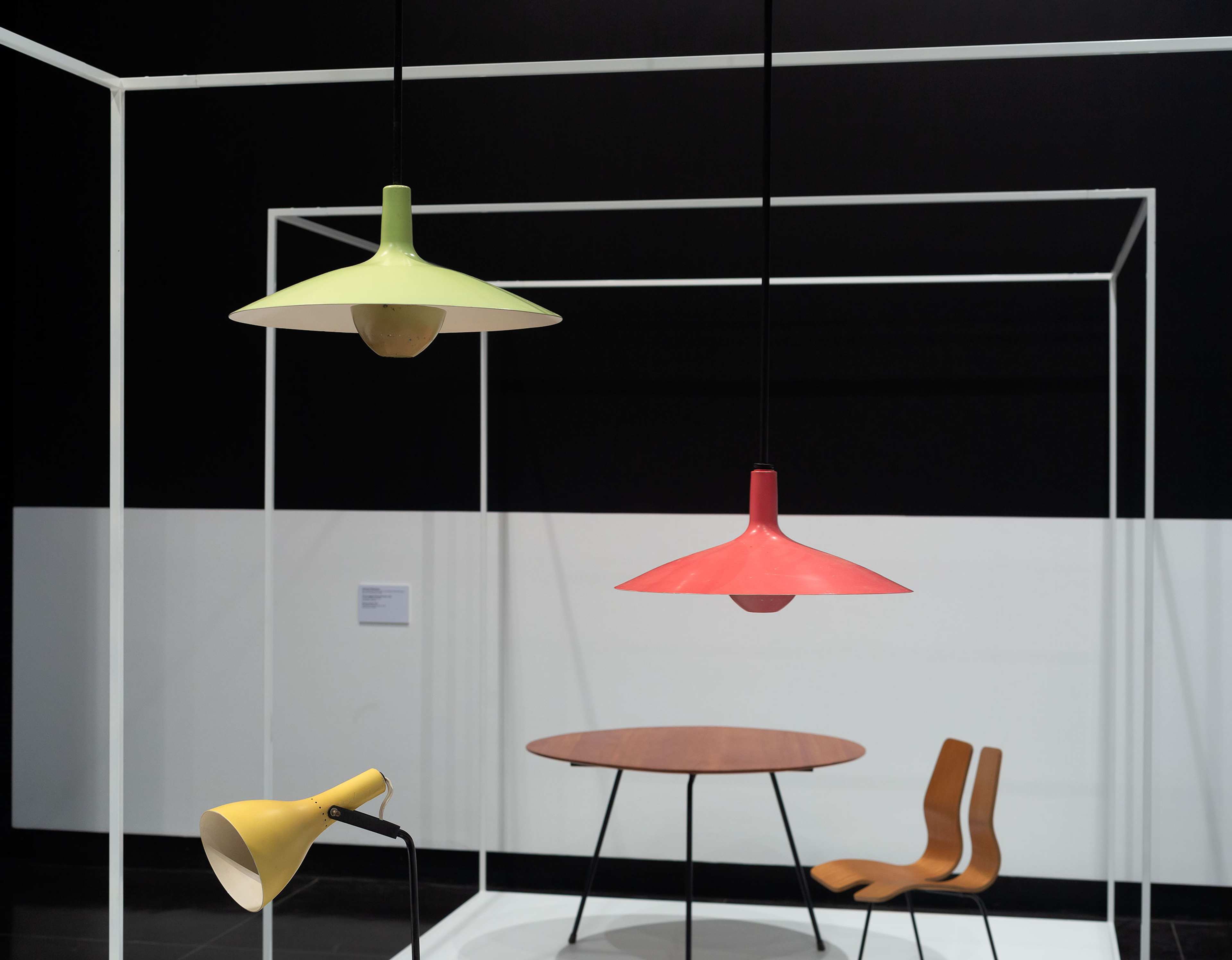 An installation of mid century brightly painted lamps with table and chair