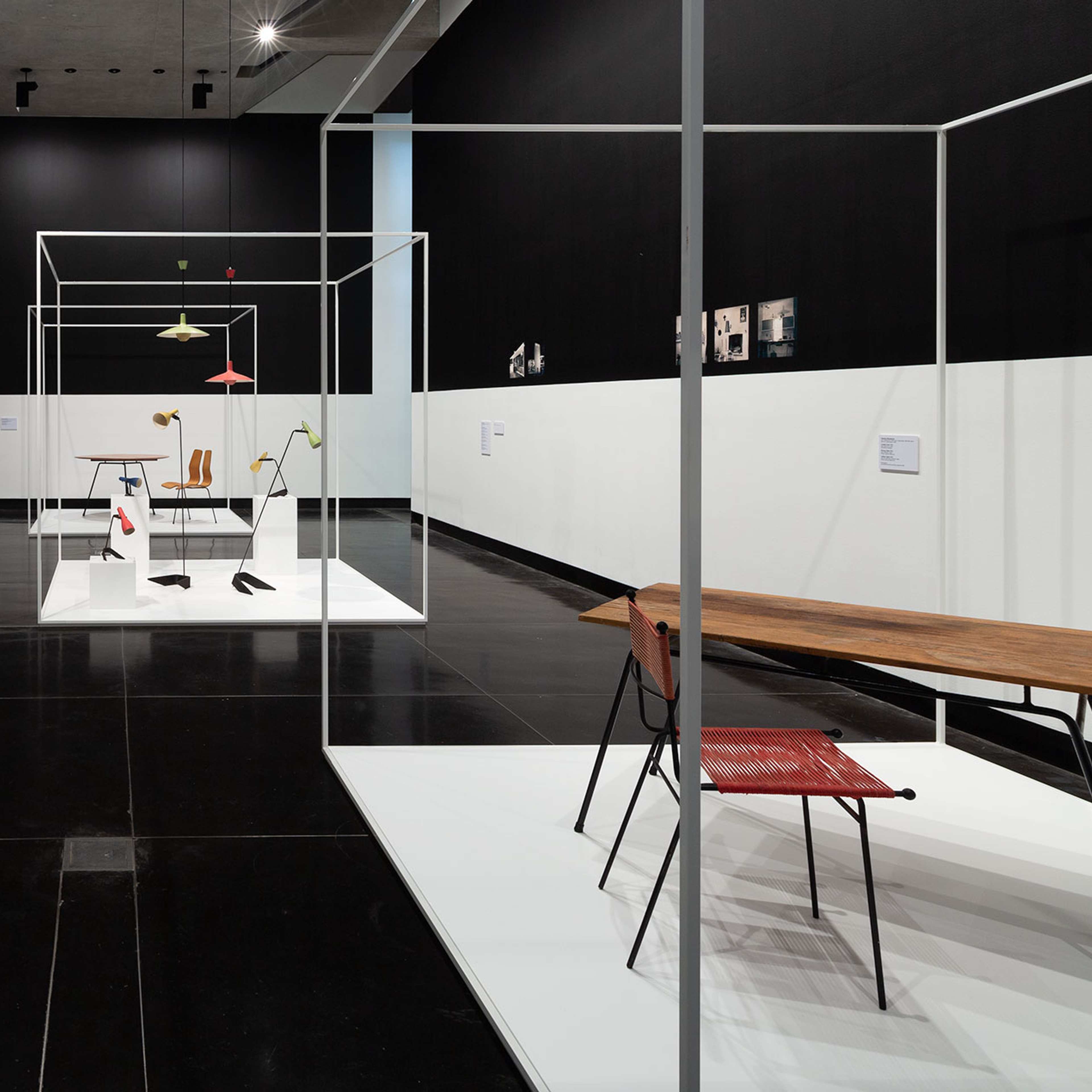 A wide shot of a gallery with mid century chairs and tables laid out in a gallery