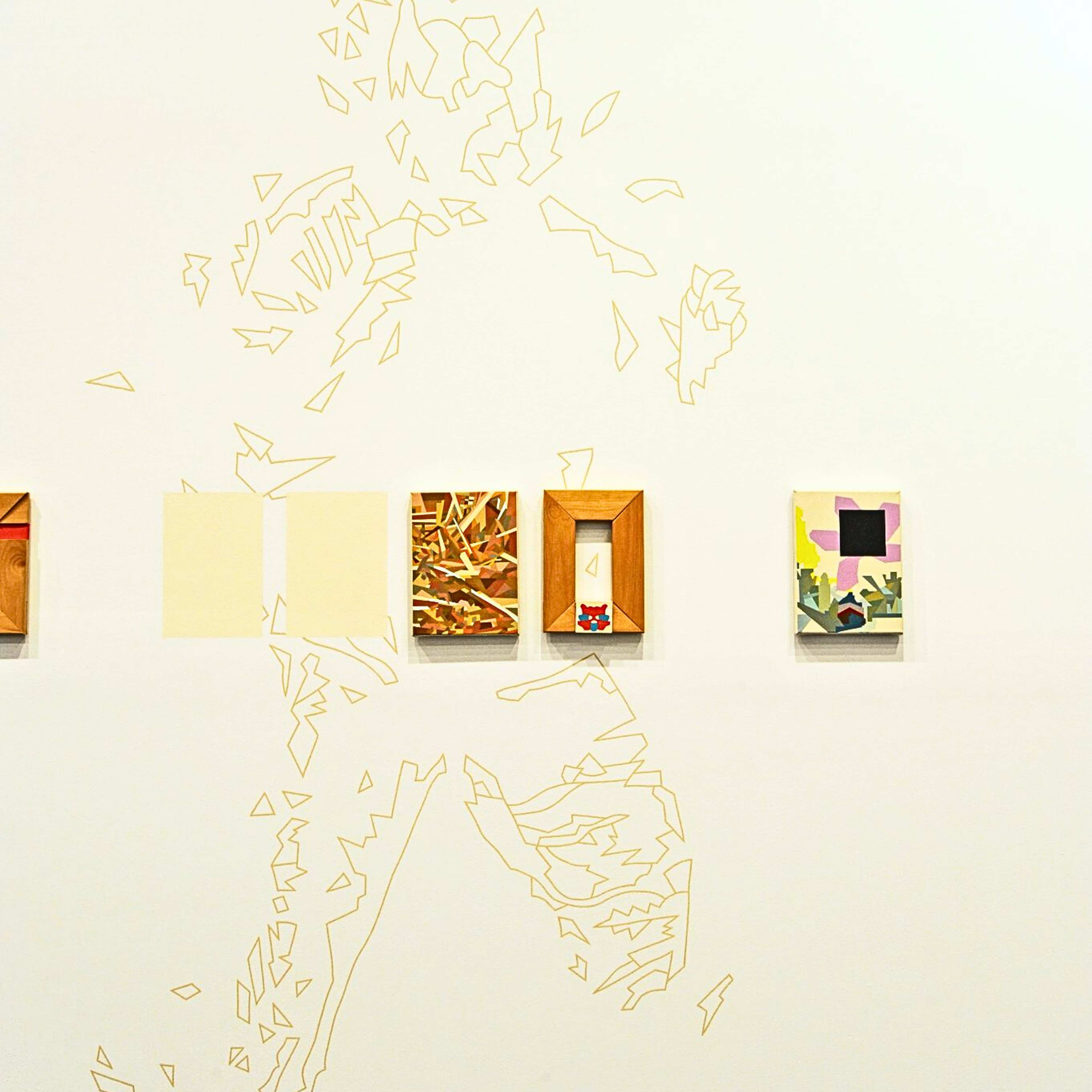 A photograph of a gallery wall with a drawn outline of a figure and small-scale wall works arrange in a horizontal row across it