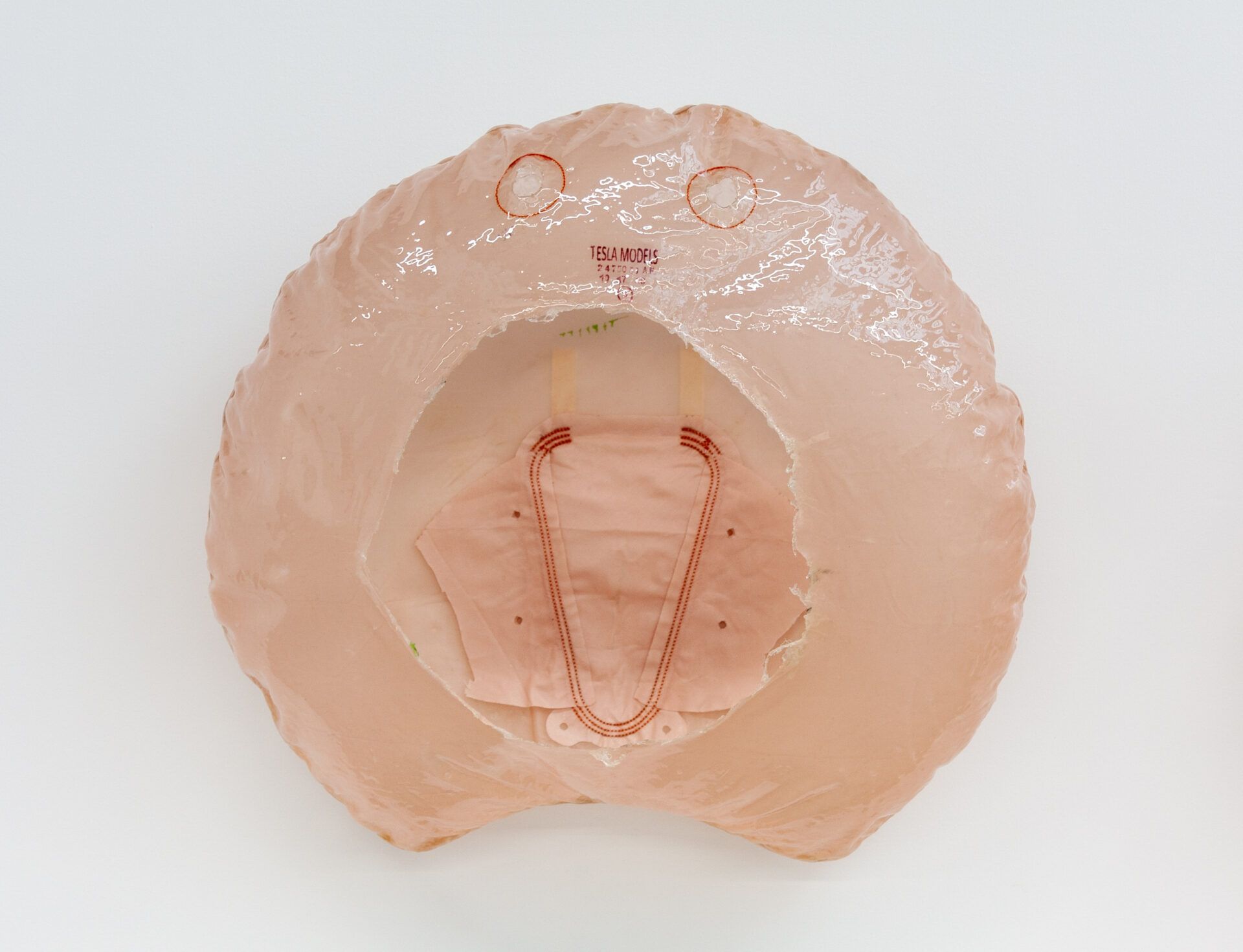 A pink air bag with a hole with red round circles resembling eyes with text starting Tesla models