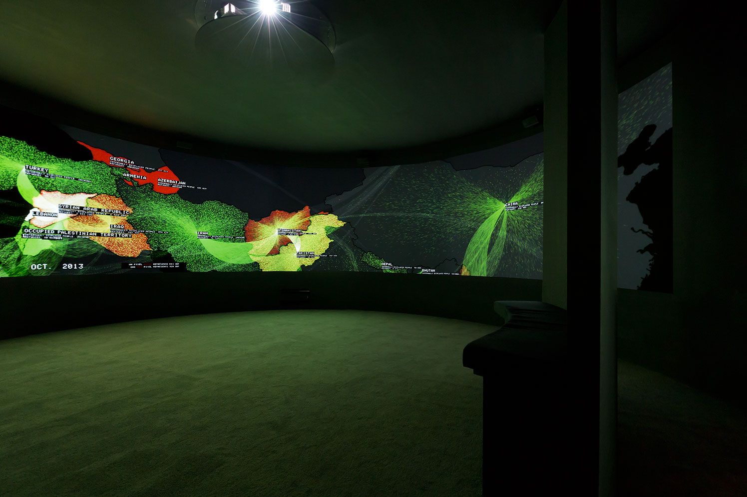 Wrap-around-the-room projection of an infographic featuring a map overlaid with bright coloured lines 