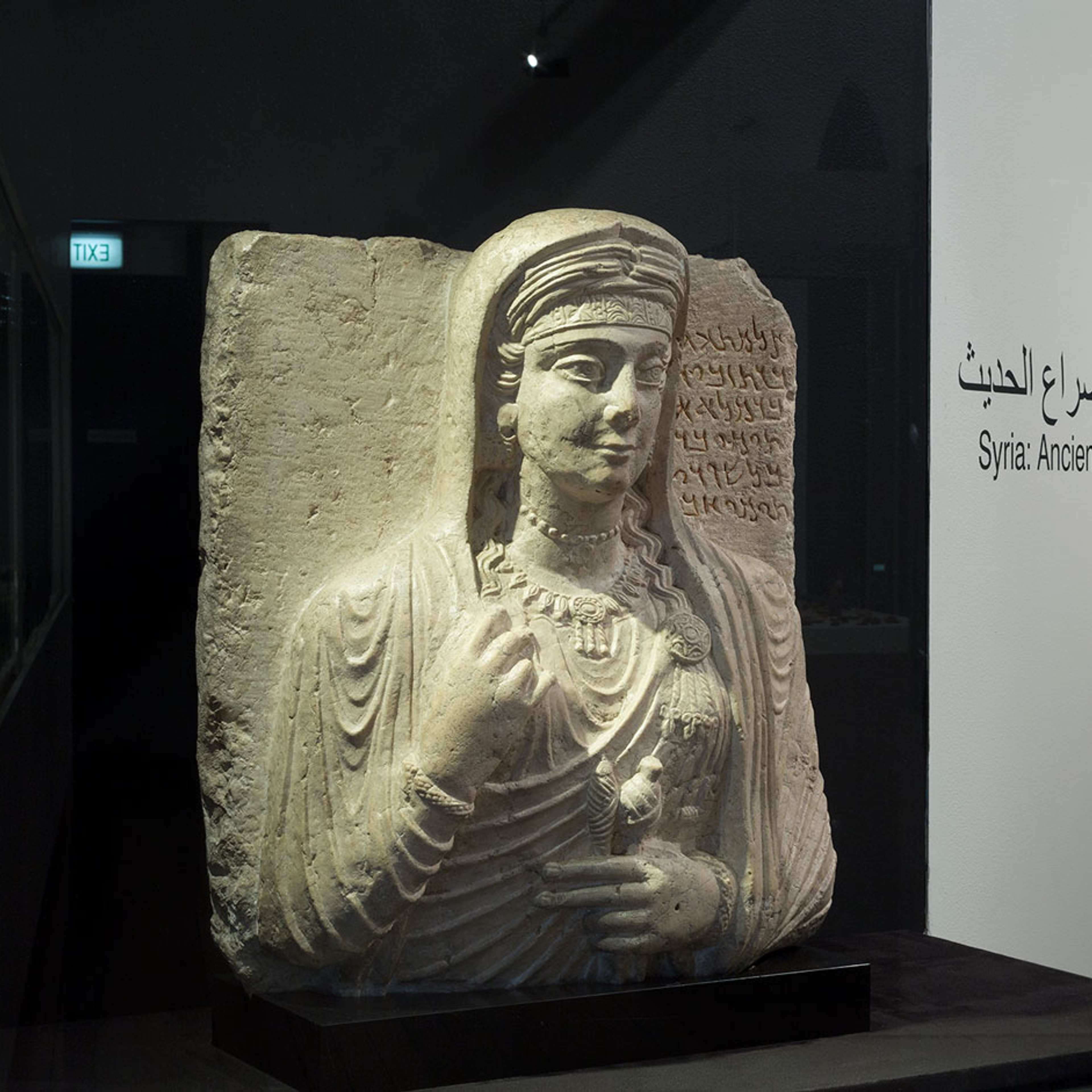 A terracota female head statue on a black wall