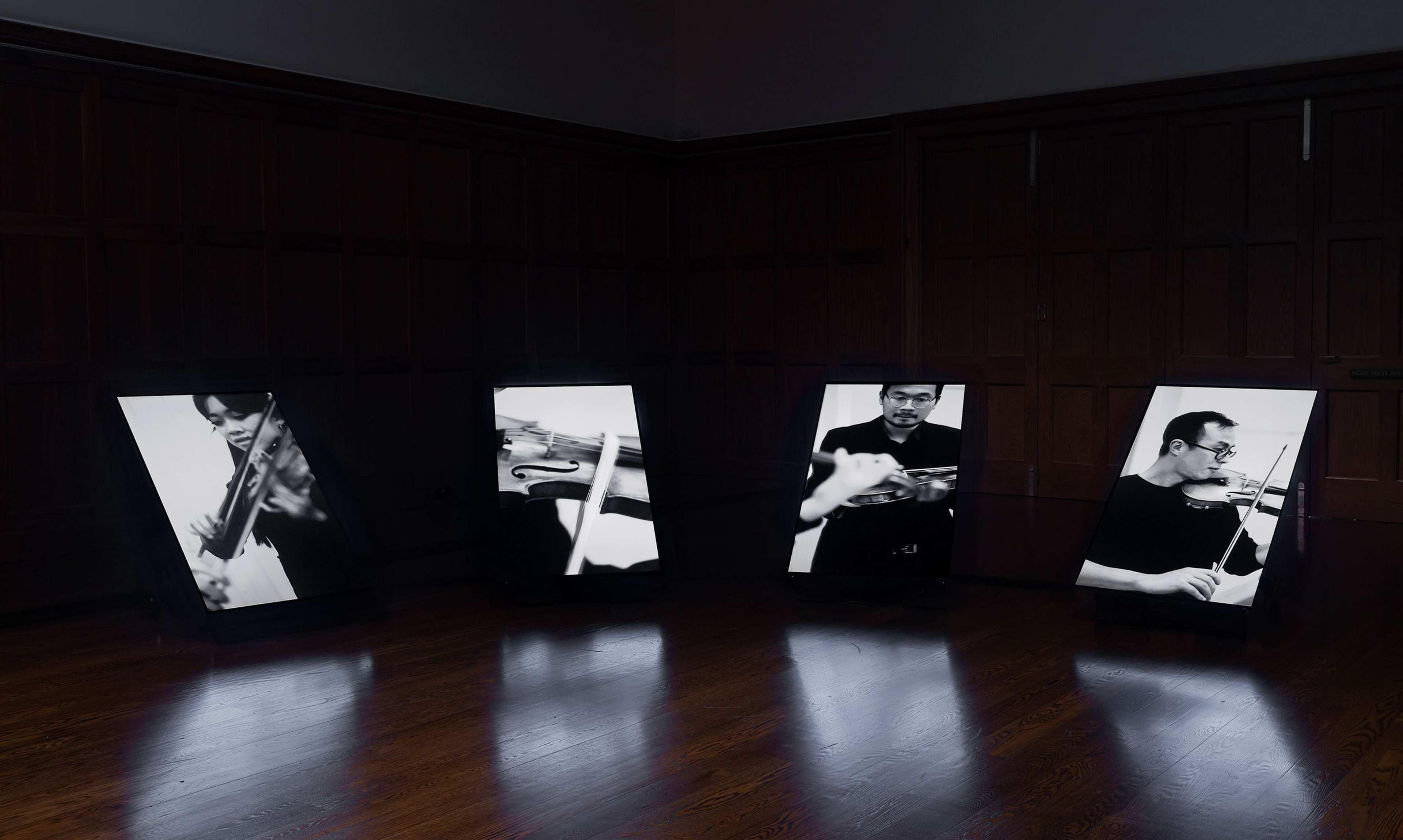 Four portrait screens showing musicians playing violin in black and white
