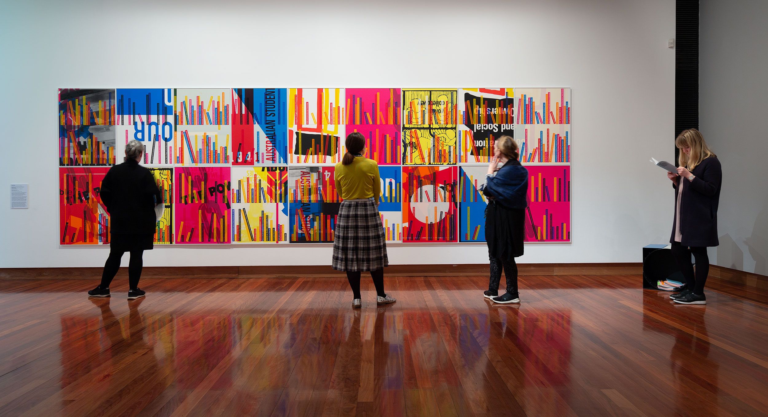 Visitors look at a colourful artwork in a gallery