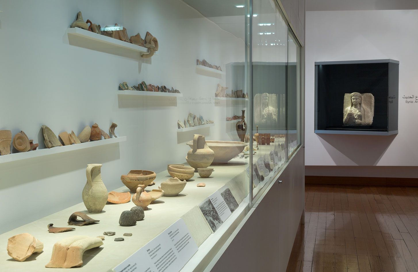 A photograph of a gallery with a large vitrine displaying a large array of ancient ceramics