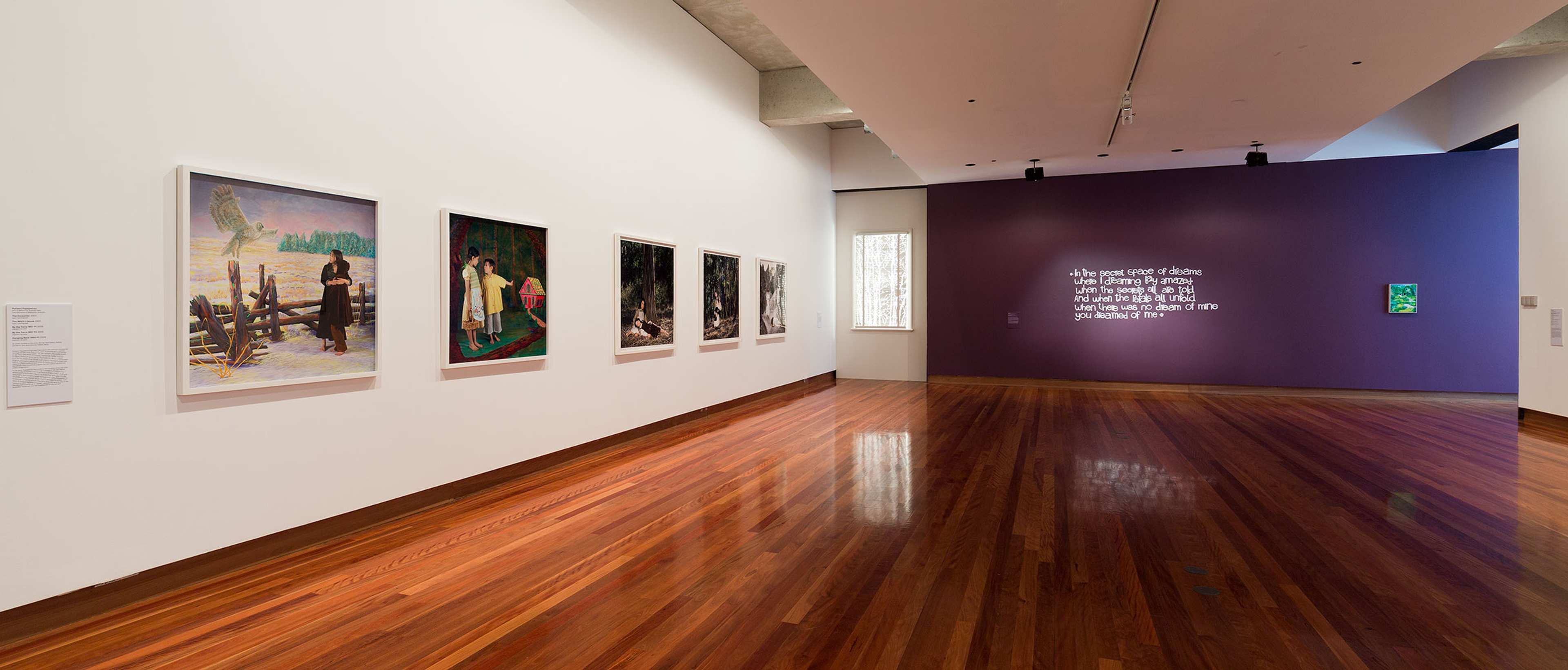 A photograph of a gallery space with multiple works in different media on the walls