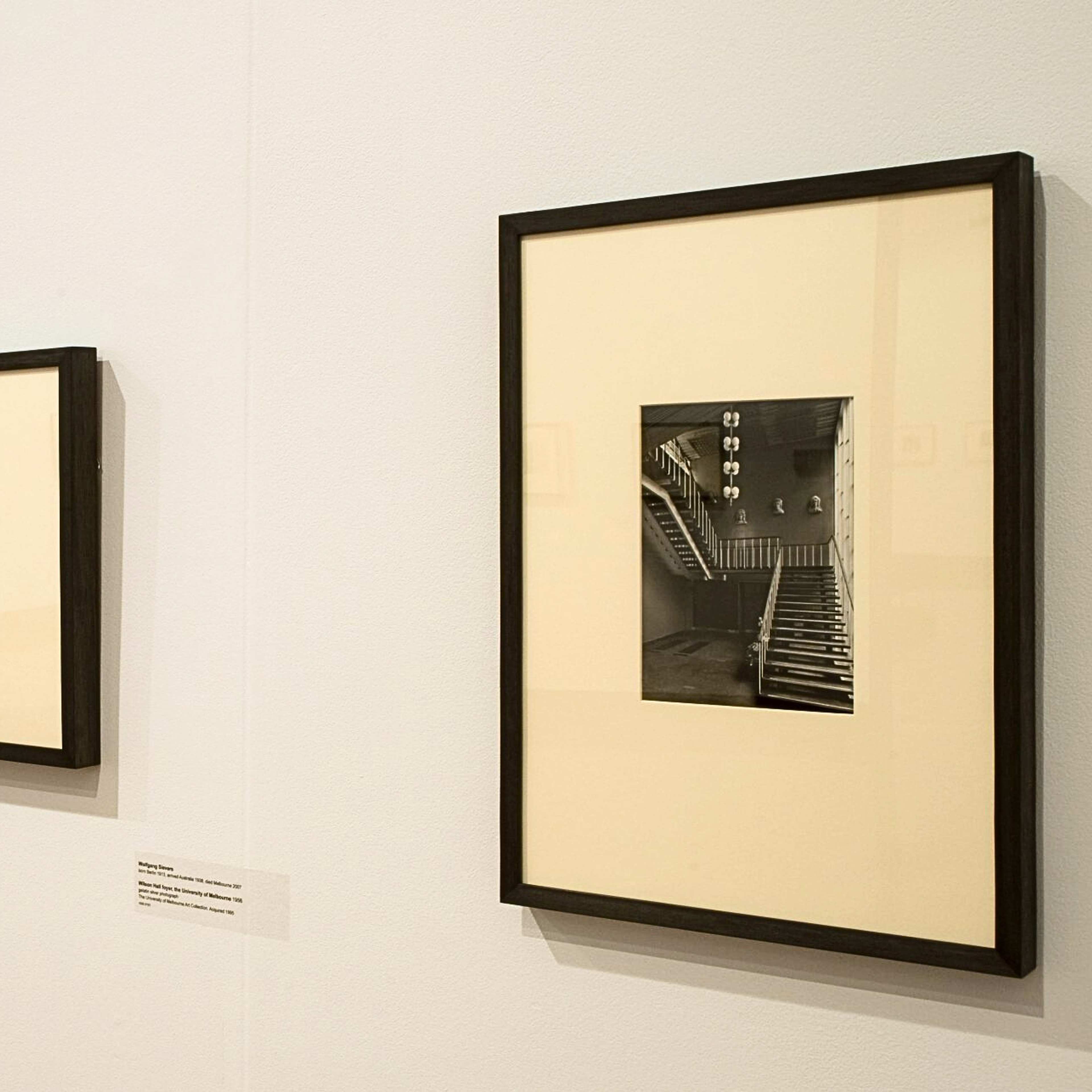 A photograph of three black and white framed photographs of interiors accompanied by labels