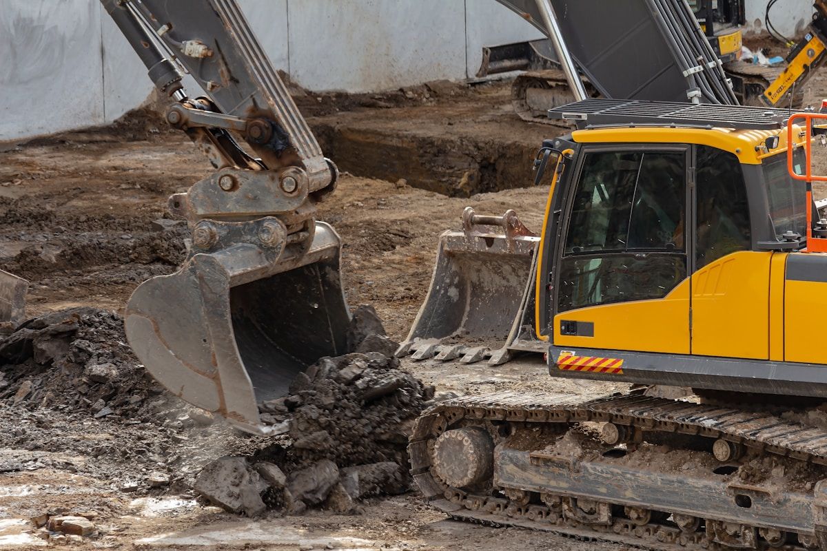 Yellow excavator on construction site for trenching and excavation safety consulting