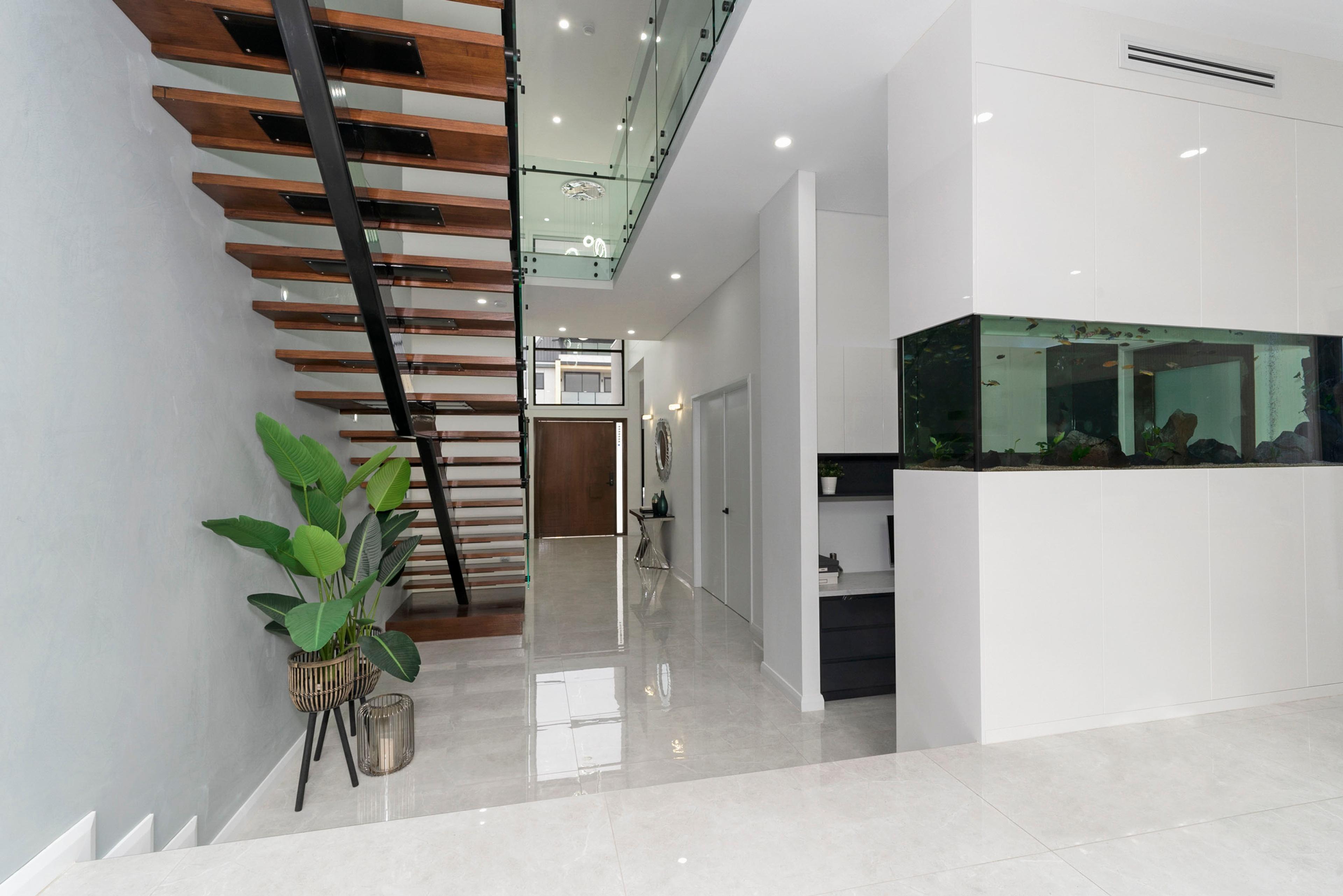 Dezire Homes build, floating staircase in an open living room with feature wall with aquarium
