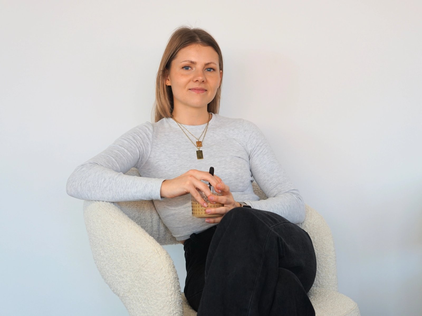 Portet van Sarah zittend op witte stoel tegen witte achtergrond