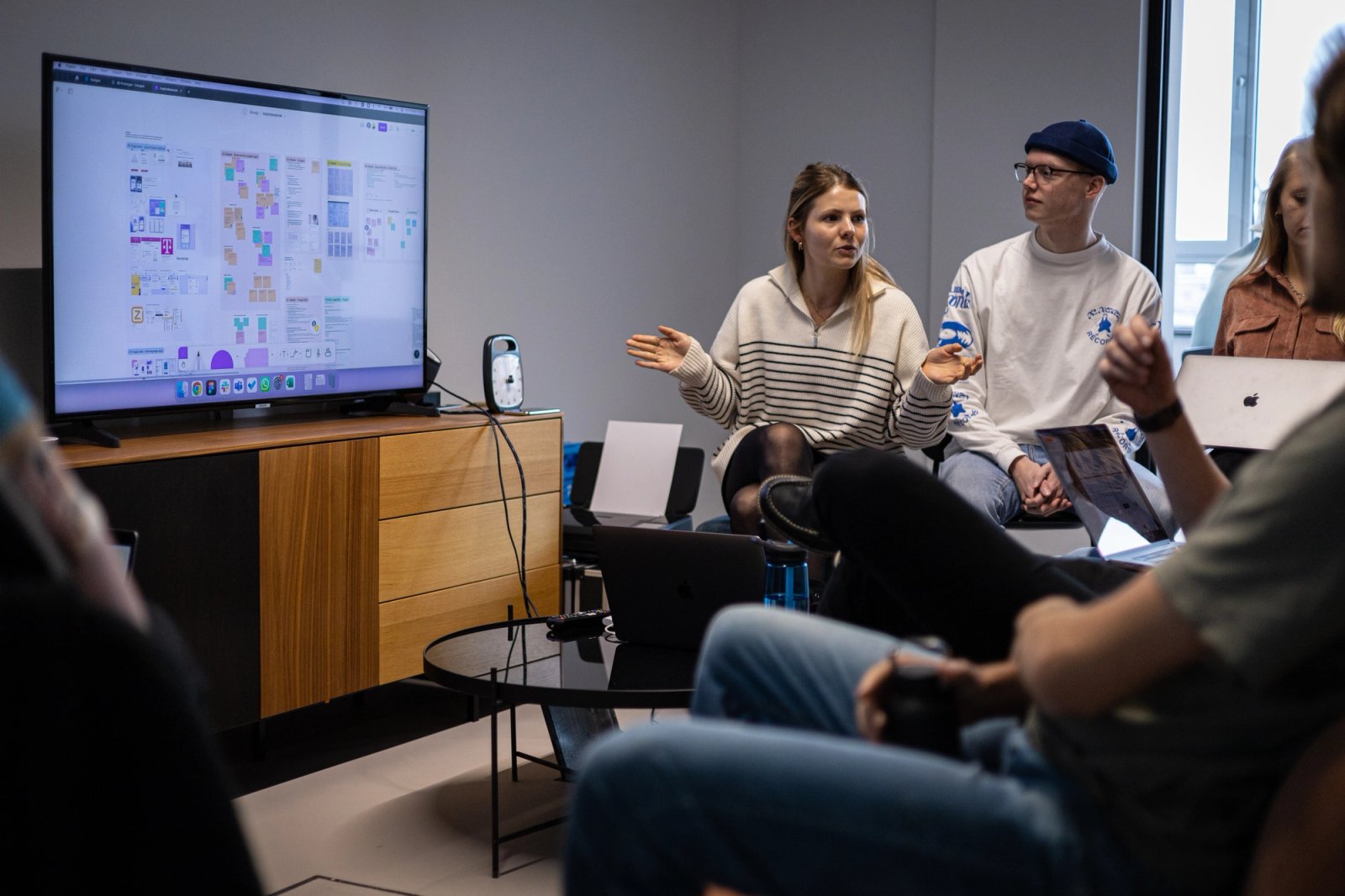 Presentatie voor een tv scherm met een aantal mensen daaromheen.