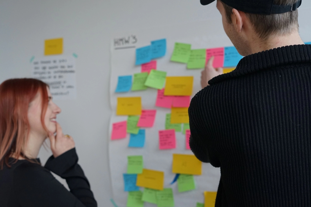 Foto van twee humanoids collegas die brainstormen voor een muur met post-its