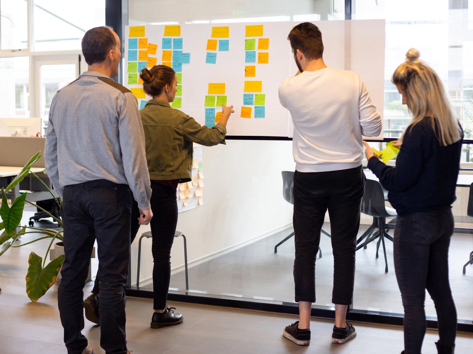 Onze UX designers staan rondom een glazen wand met post-its