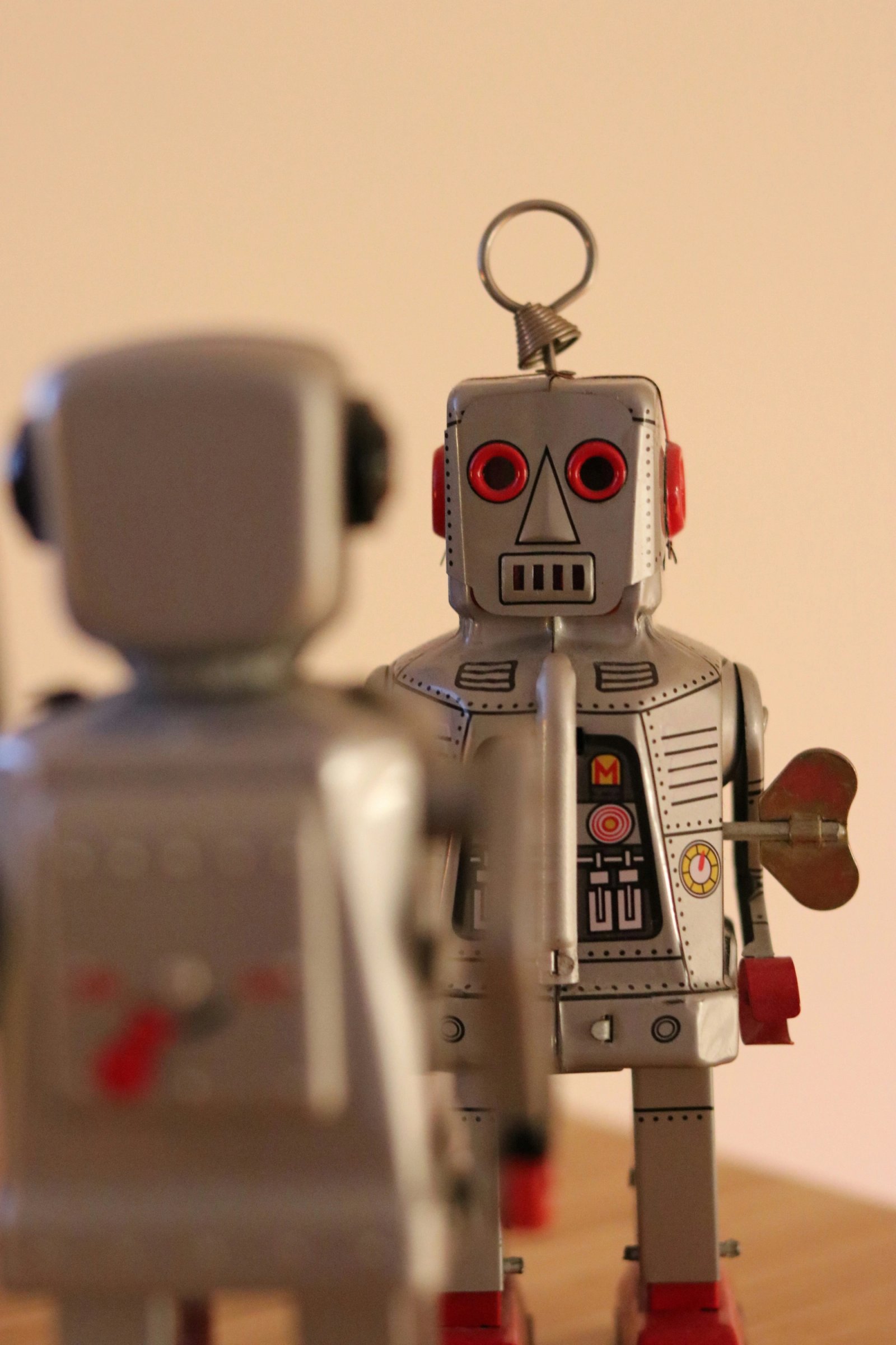 Twee vintage blikken robots staan tegenover elkaar in een gesprekssituatie. De afbeelding symboliseert reflectie op kunstmatige intelligentie — technologie die naar zichzelf kijkt en kritisch bevraagd wordt.