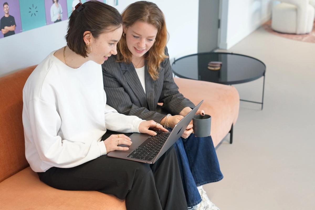 Twee UX designers van Humanoids zitten op een bank met een laptop