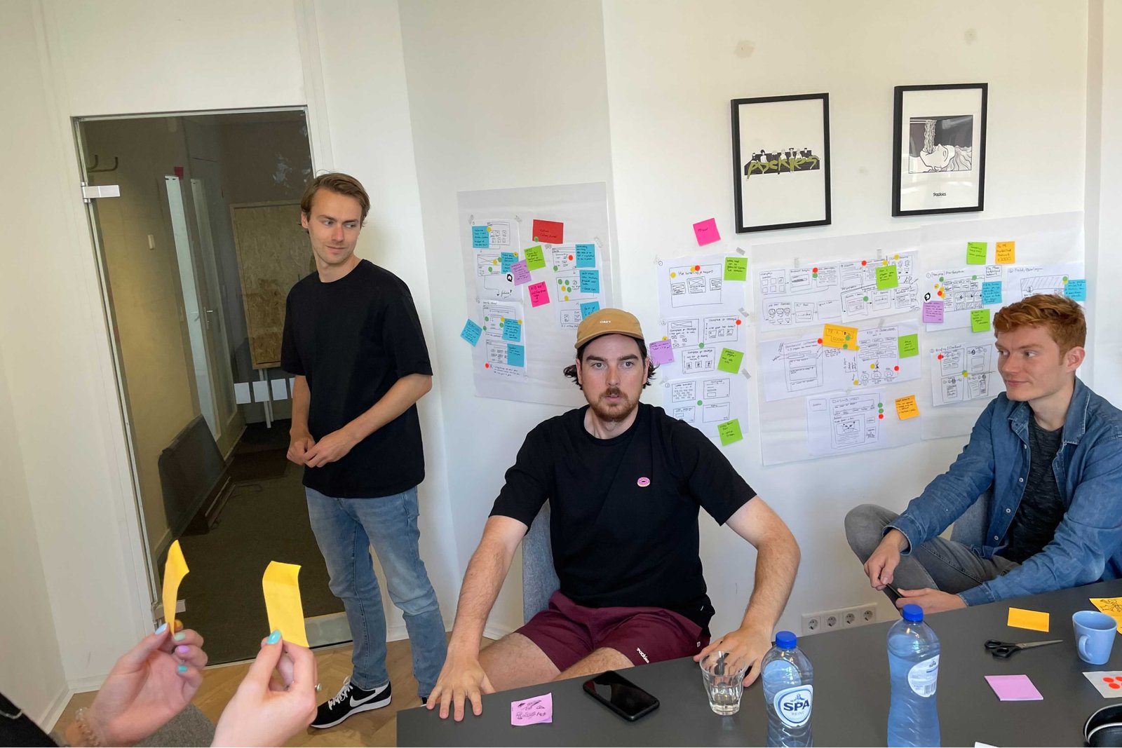 Medewerkers aan het werk voor een design sprint muur met post-its.
