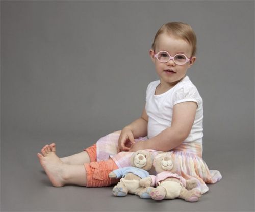 Una bebe con lentes sentada.