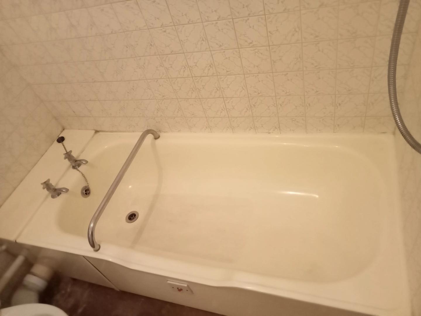Clean white bathtub with a tiled surround after cleaning