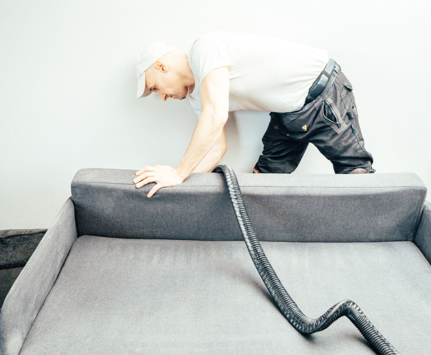 Cleaner deep-cleaning the cushions of a grey sofa