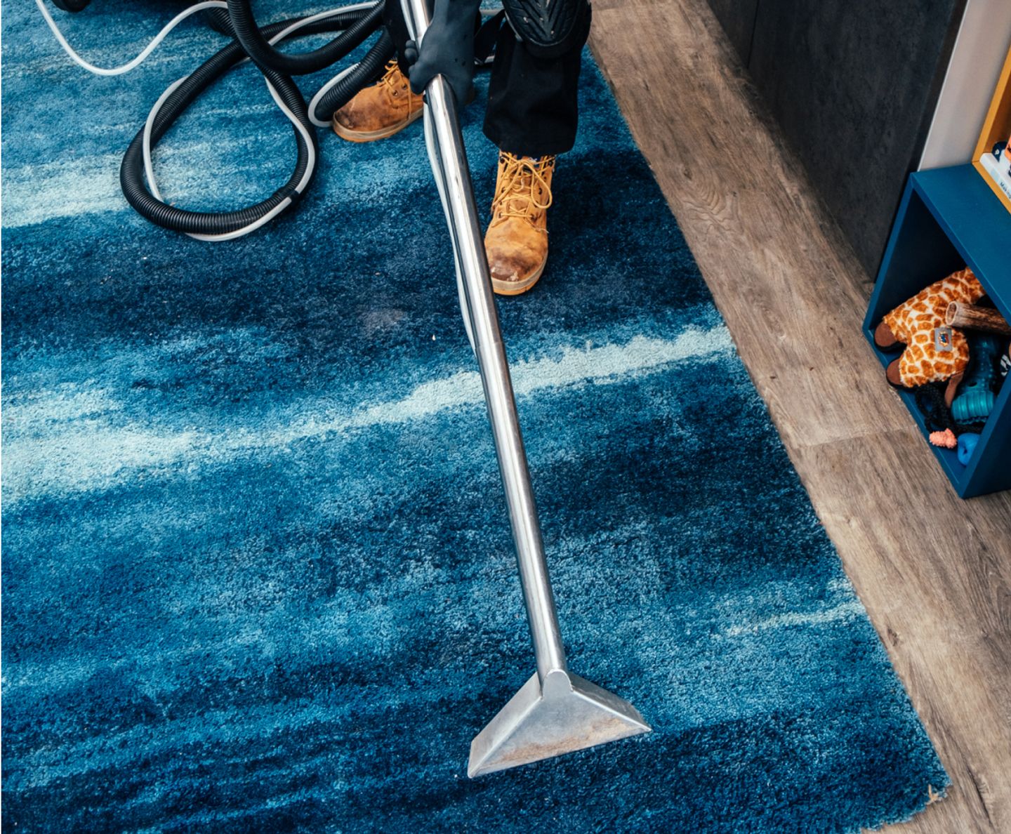 Cleaner using a carpet-extractor wand on a blue rug