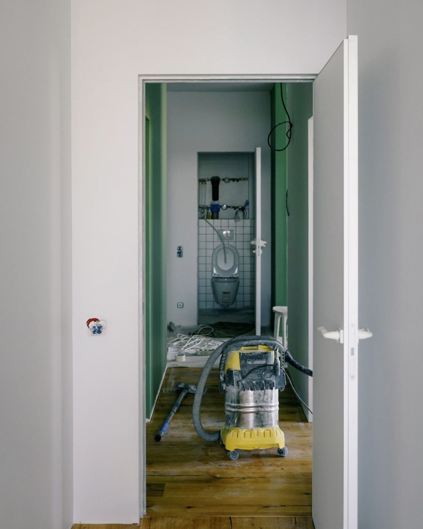 Industrial wet-and-dry vacuum in a doorway of a room being renovated