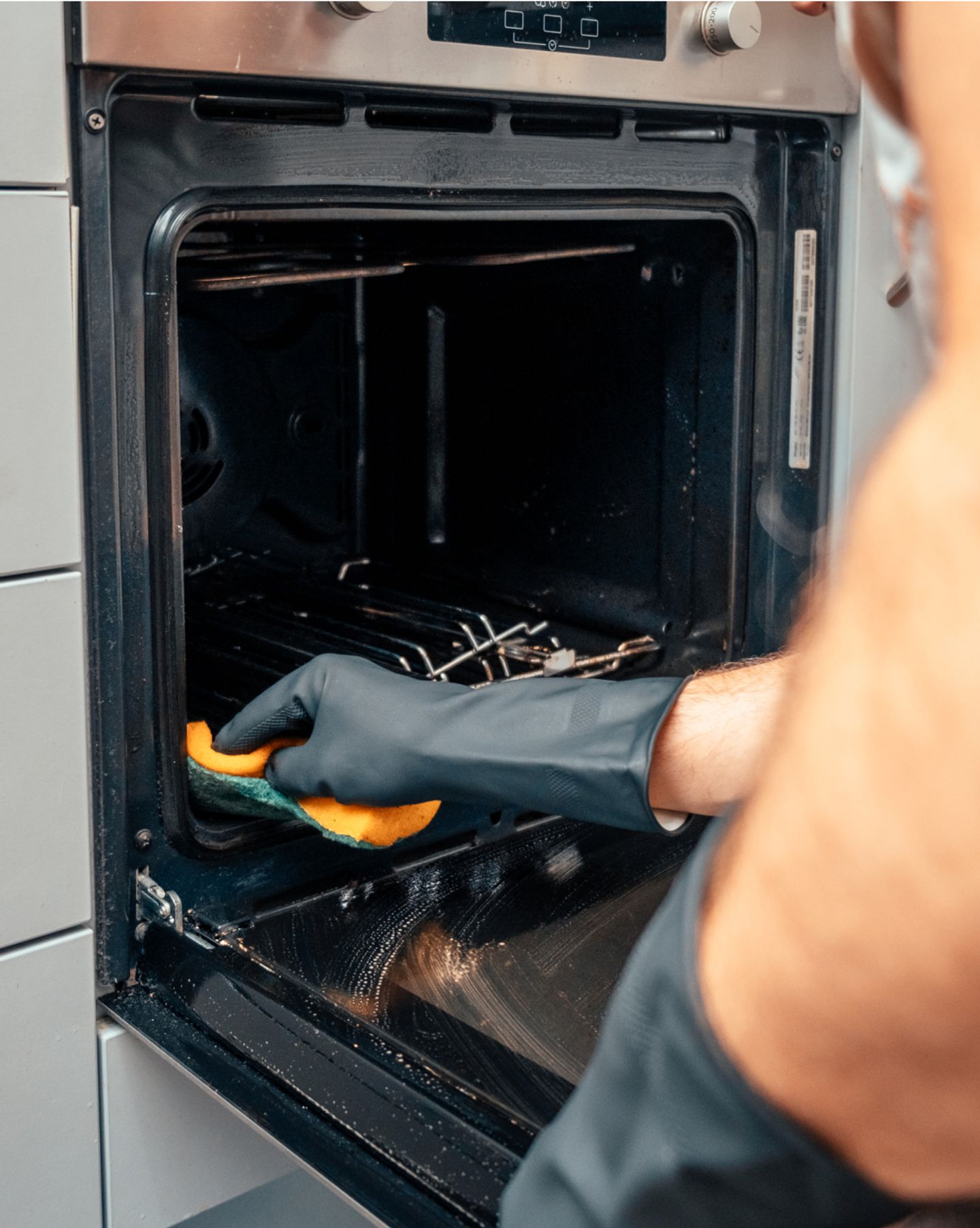 Cleaner scrubbing the racks and interior of an oven